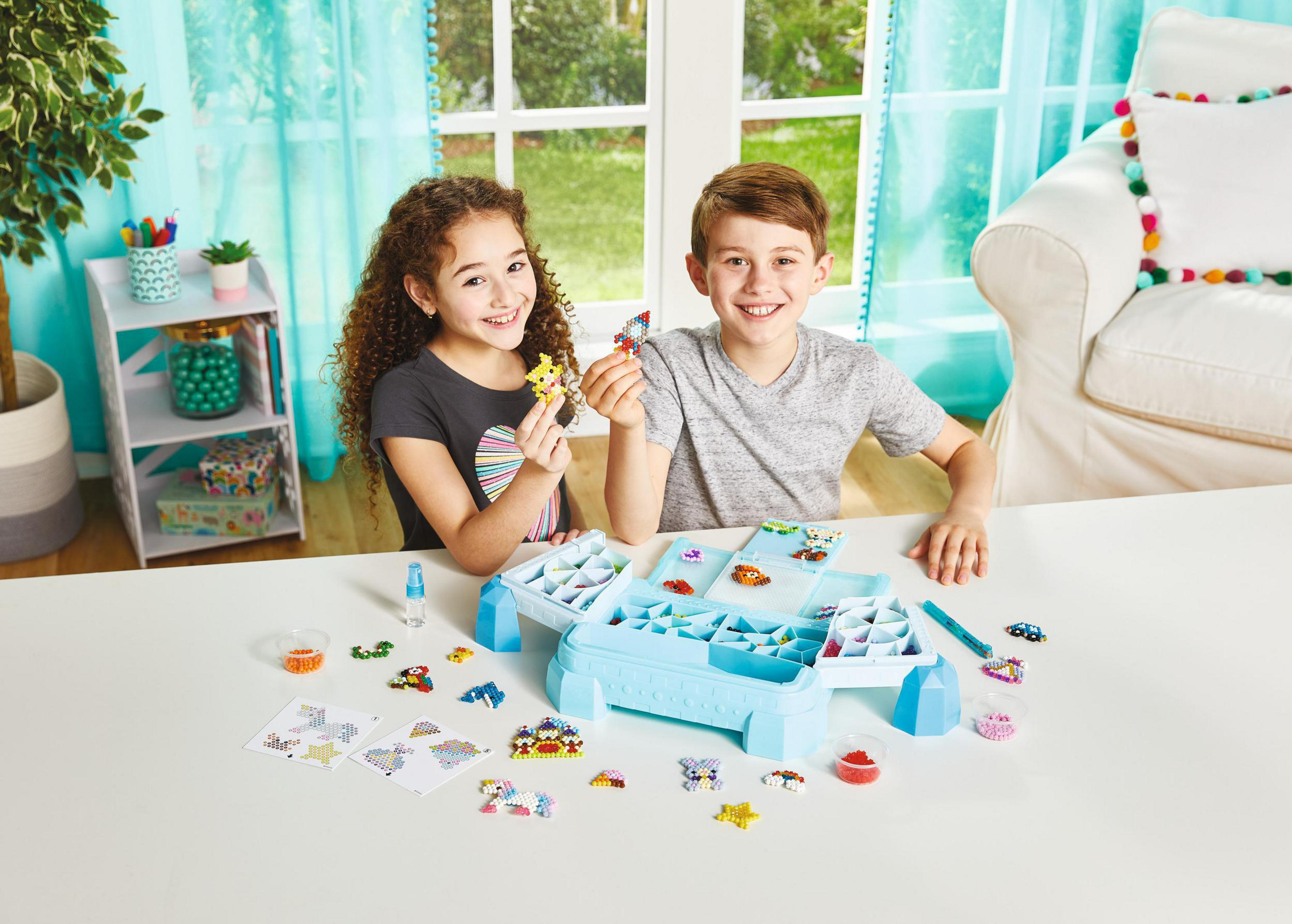 Due bambini con perline giocattolo. Tavolo blu e bianco. Sfondo bianco.