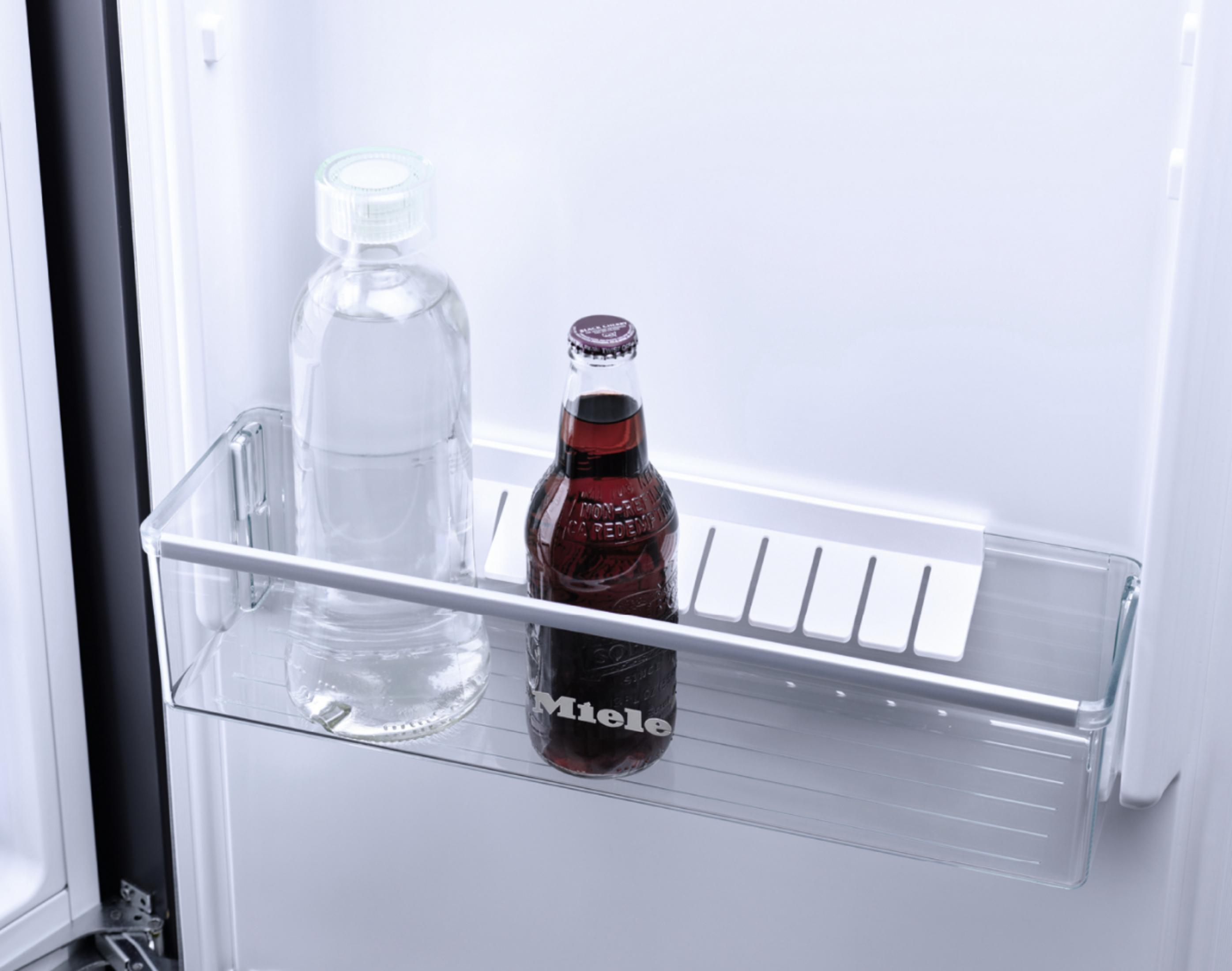 Im Kühlschrank. Eine Wasserflasche und eine Limonadenflasche stehen im Regal.