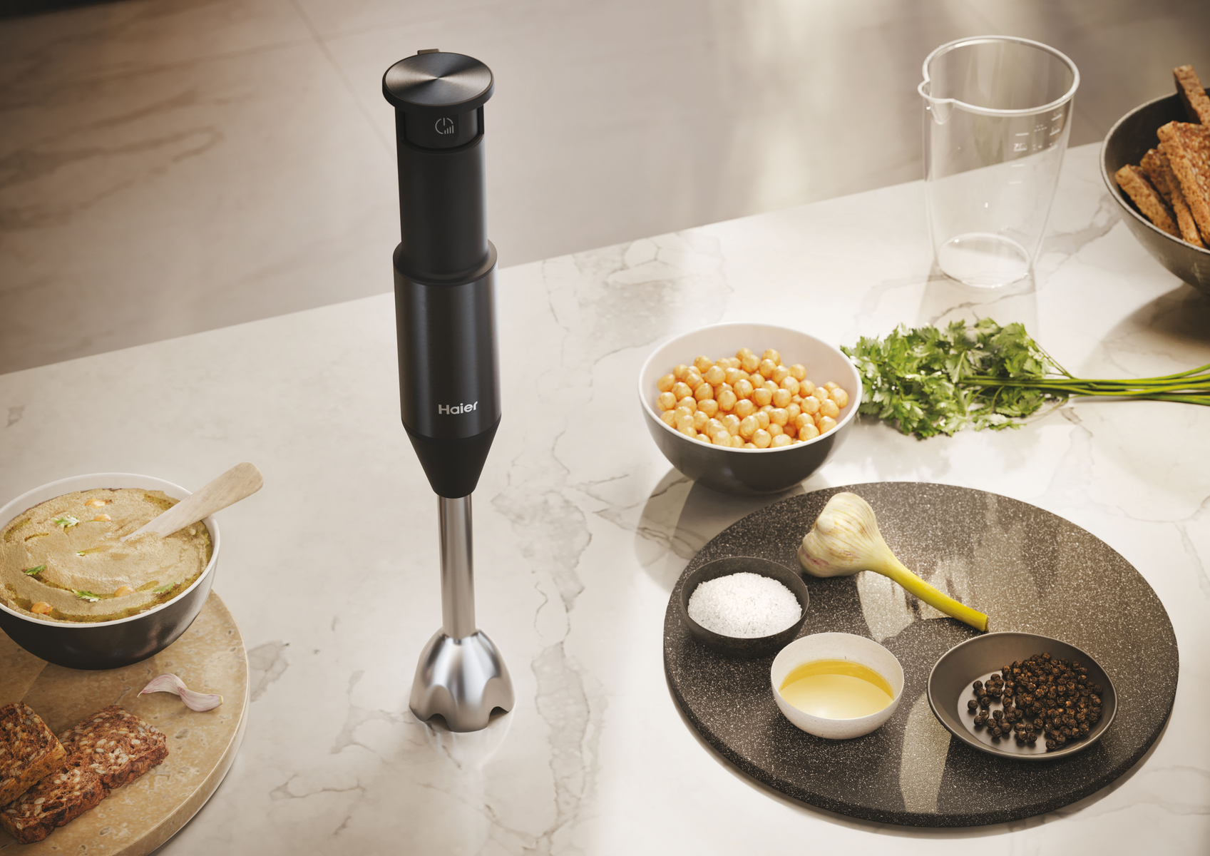 Czarny blender ręczny ze składnikami na hummus, na białej marmurowej powierzchni.