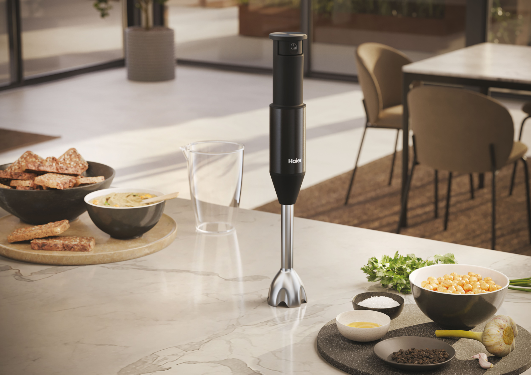 Czarny i srebrny blender ręczny na marmurowym blacie z składnikami do gotowania.