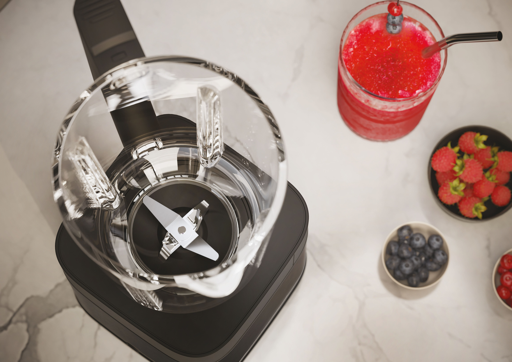 Blender ze składnikami: jagodami, koktajlem i owocami. Widok z góry na marmurowej powierzchni.