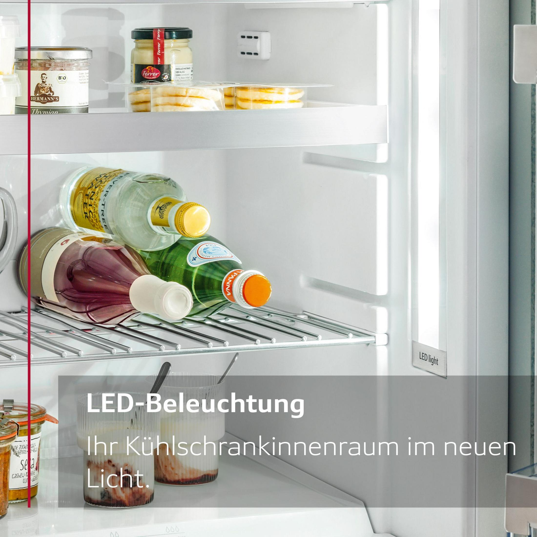 Kühlschrankinnenraum mit Flaschen, Gläsern und LED-Licht, Regale gefüllt mit Artikeln.