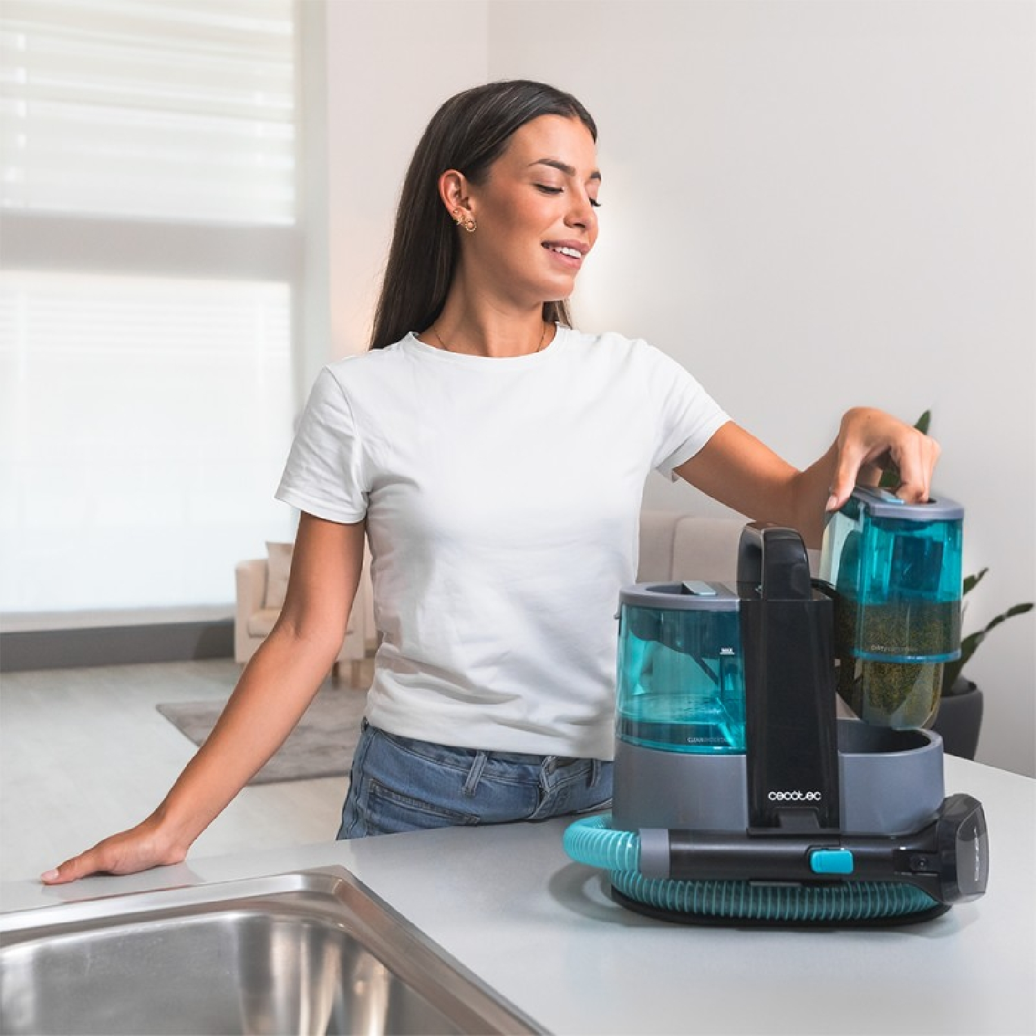 Mujer organizando piezas de aspiradora en una encimera. Cocina brillante y moderna.