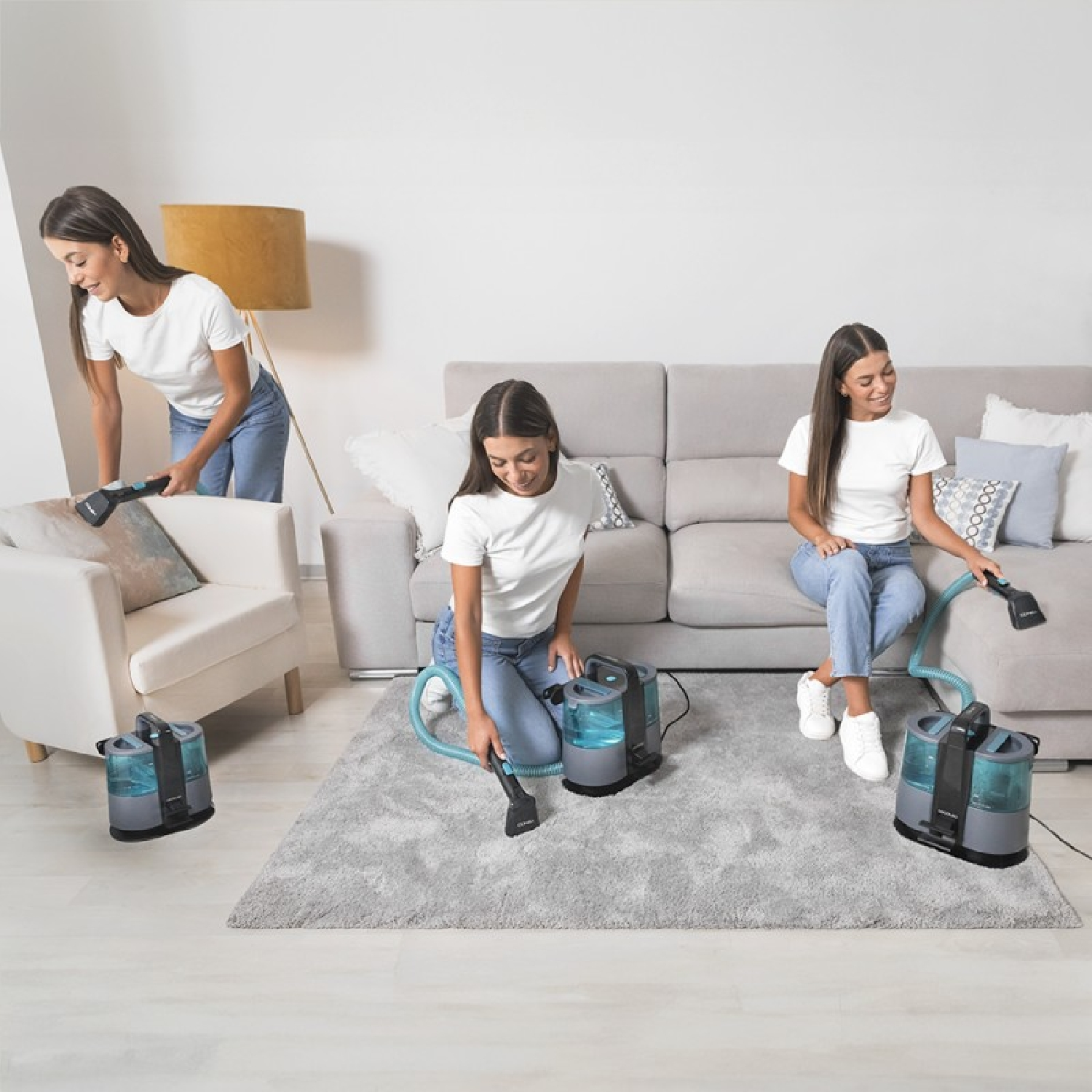 Tres mujeres limpian una habitación con una limpiadora de alfombras. La habitación tiene un sofá, un sillón y una alfombra.