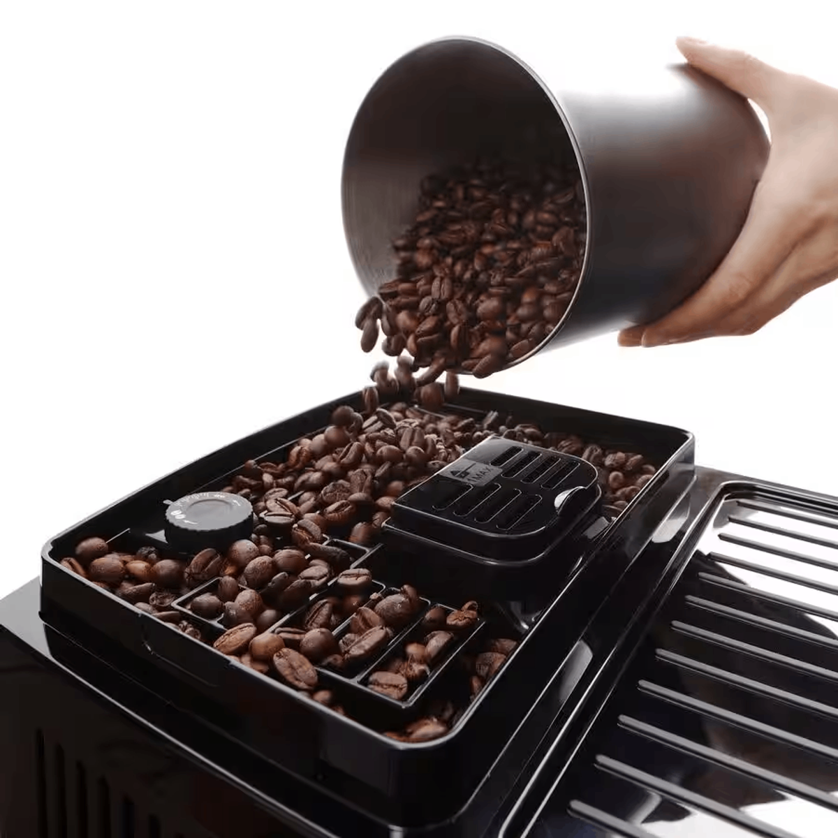 A hand pouring coffee beans into the bean container of a coffee machine, on a white background.
