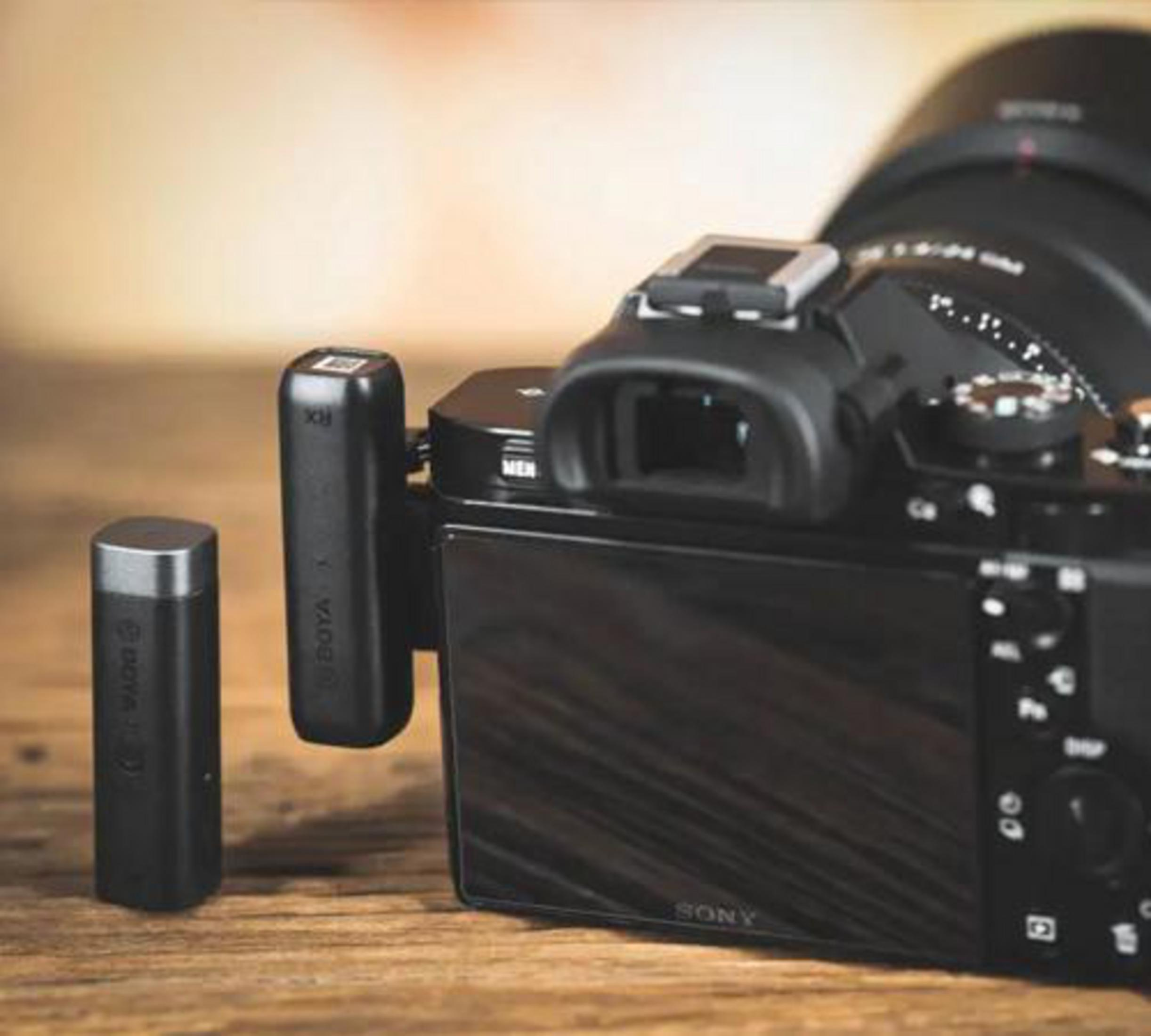 Primo piano di una fotocamera con un microfono collegato, su una superficie di legno.