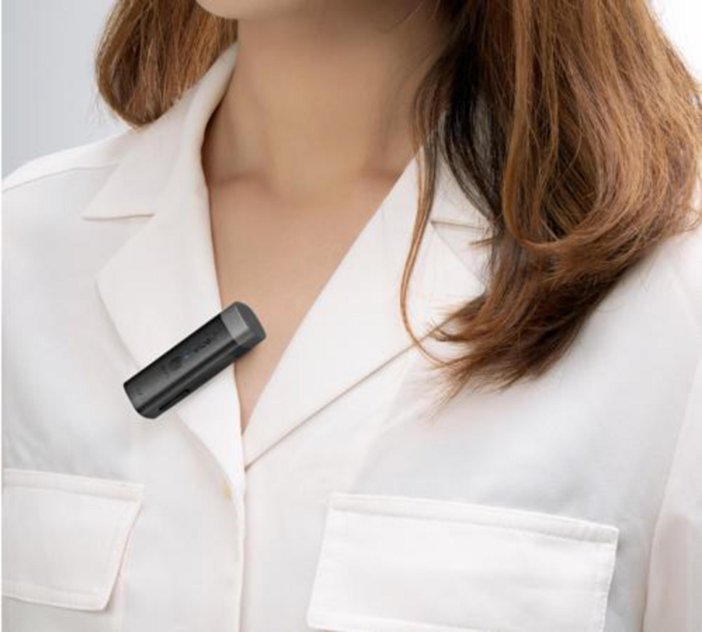 Donna con microfono nero attaccato al colletto della camicia.