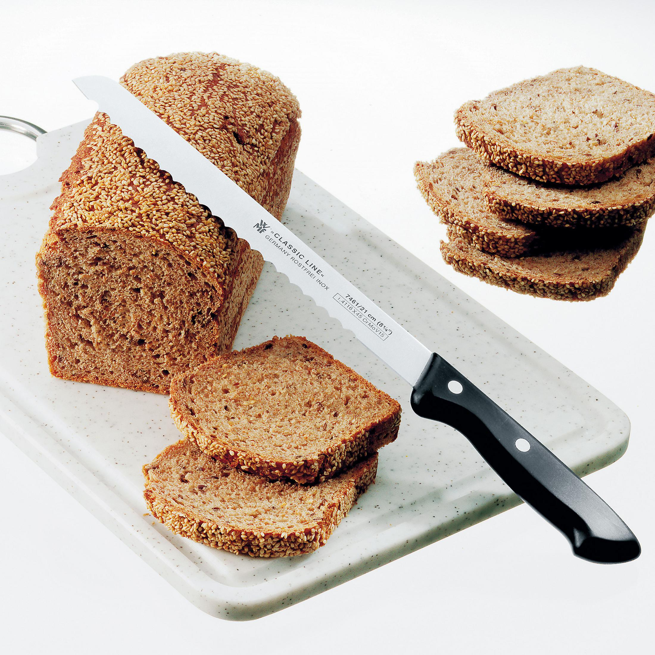 Nóż do chleba krojący bochenek chleba na desce do krojenia.