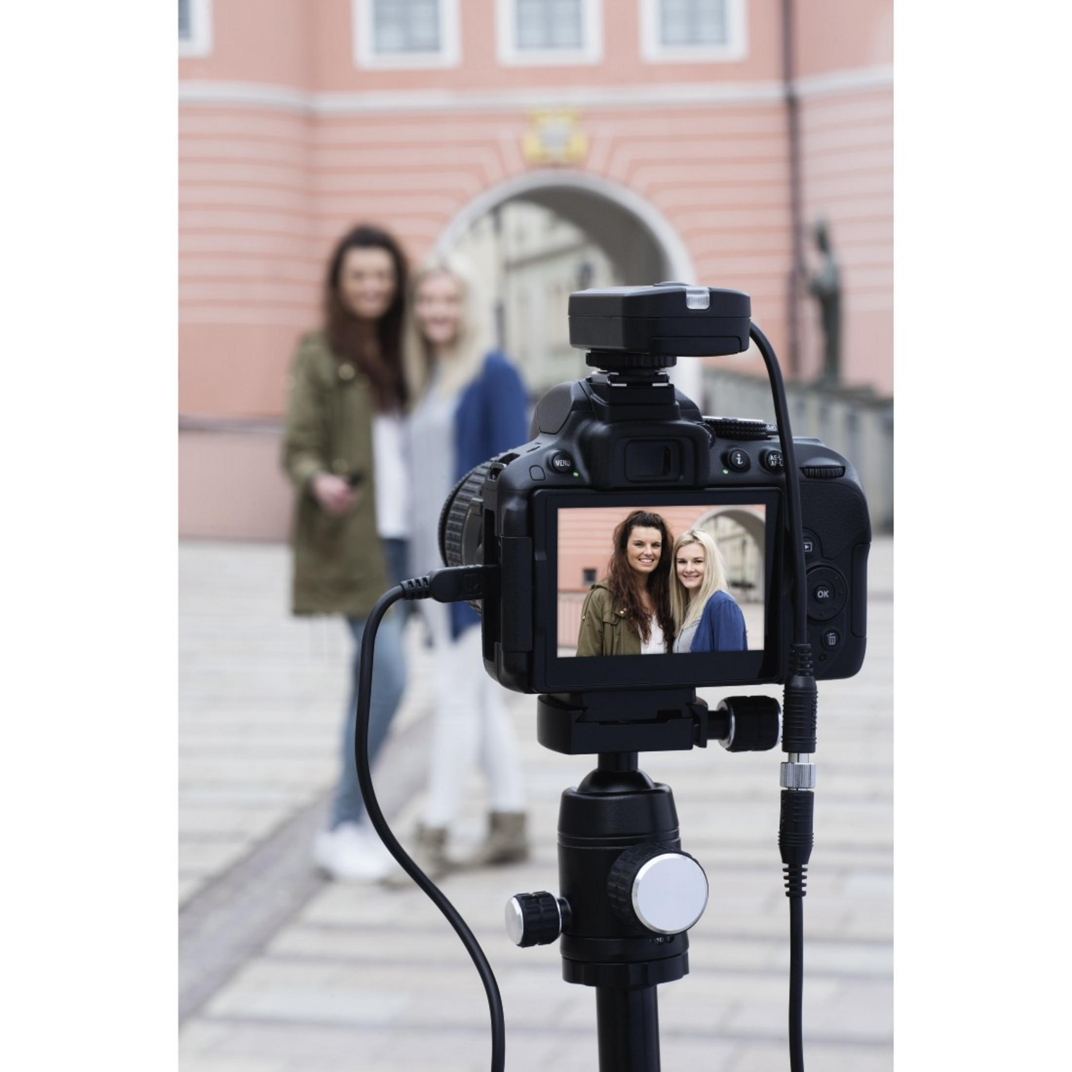 Kamera auf Stativ. Zwei Frauen im Hintergrund, Kamerabild zeigt Selfie.