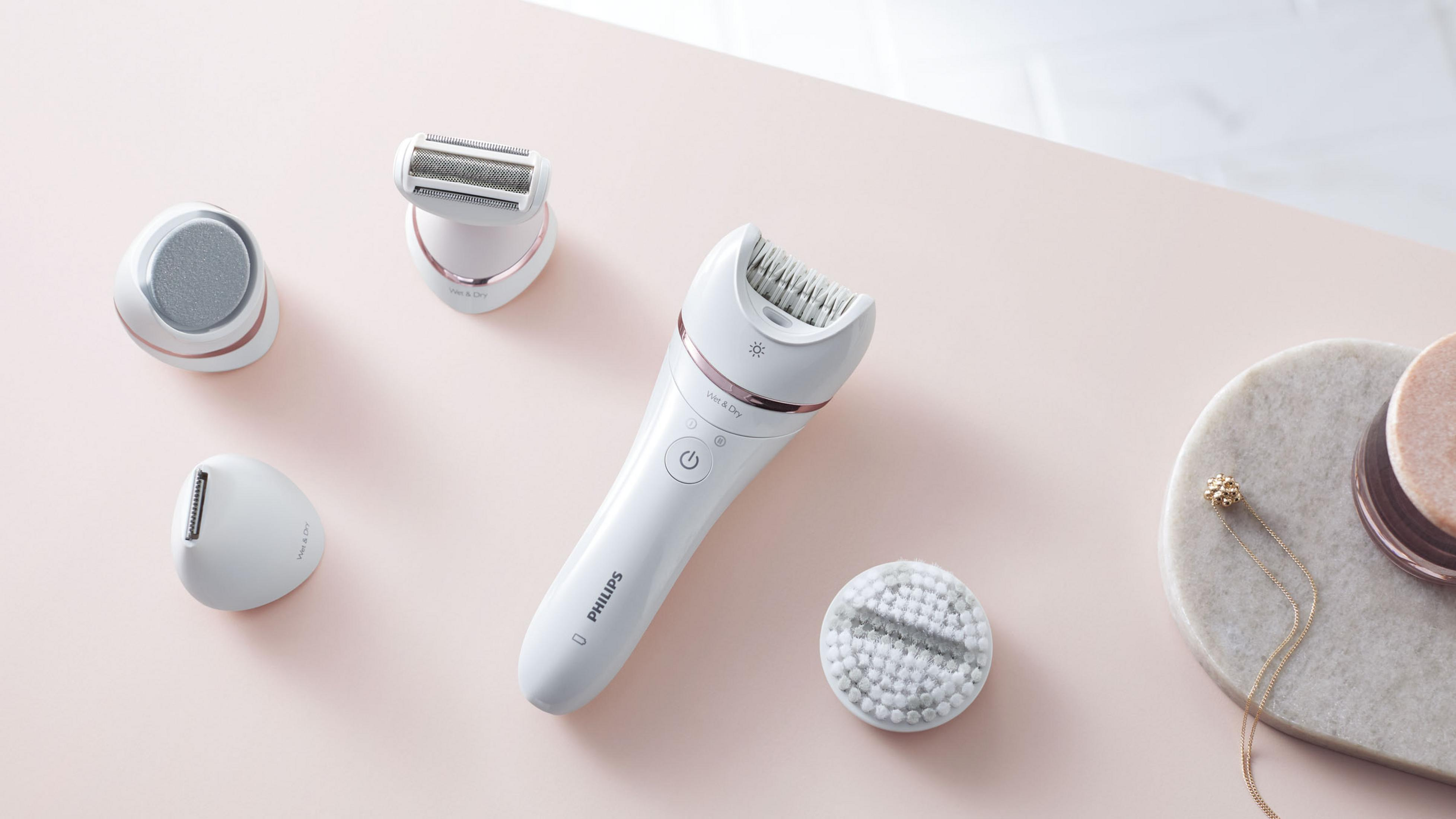 Depiladora Philips blanca y oro rosa con varios accesorios.