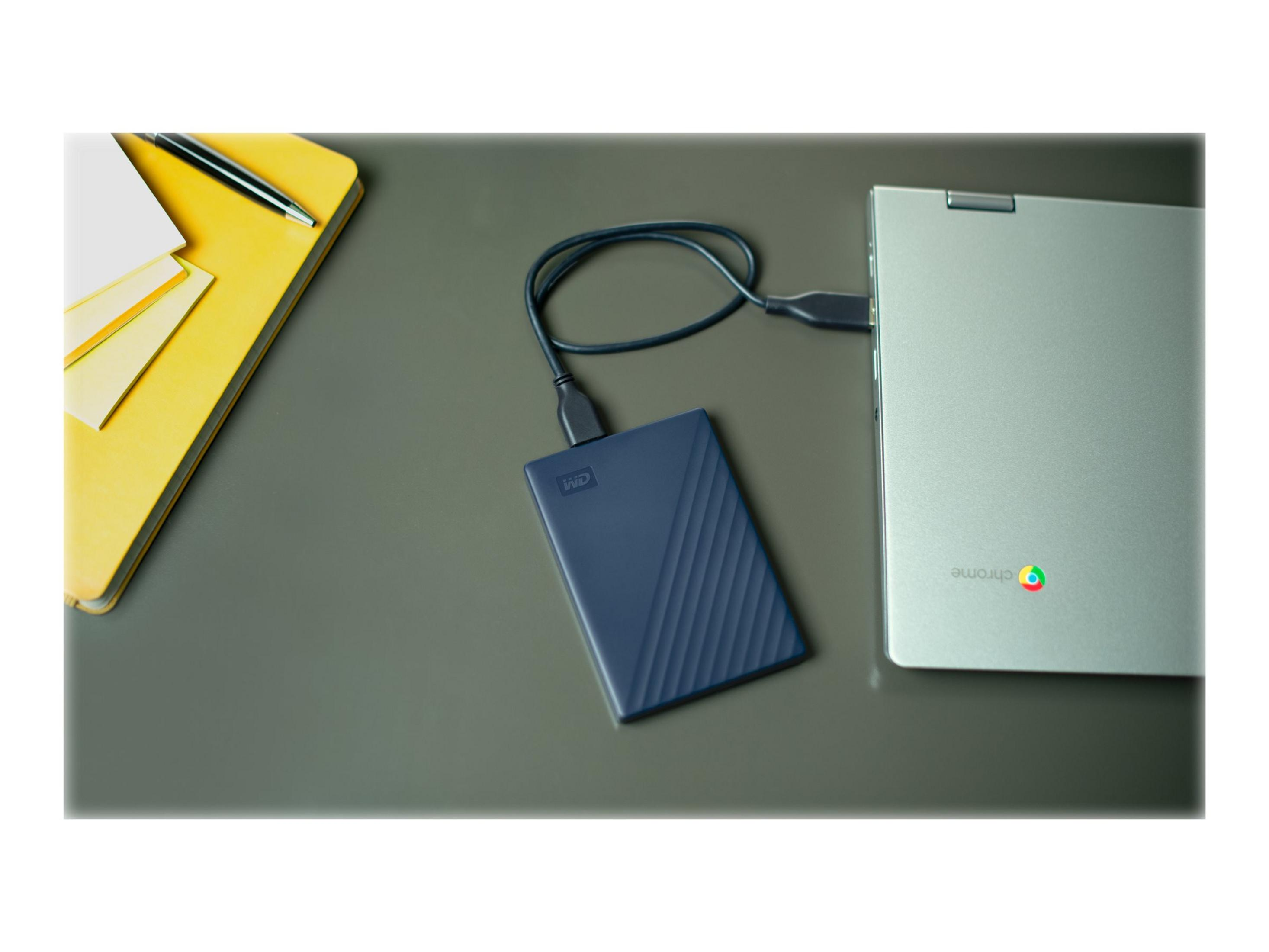 Granatowy przenośny dysk twardy podłączony do laptopa na biurku.