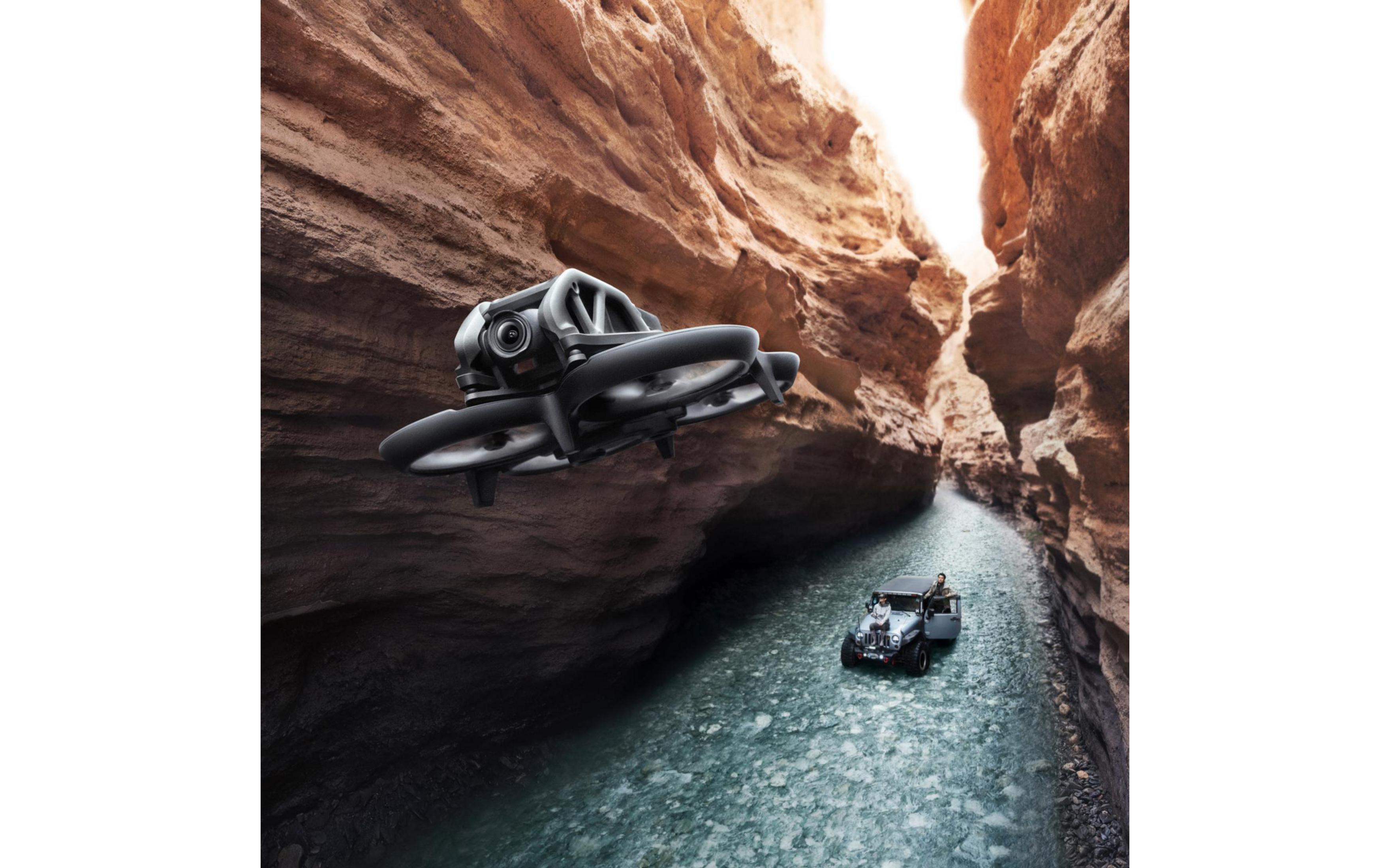 Dron volando en un cañón. Un coche pequeño está en el agua. El dron tiene una cámara.