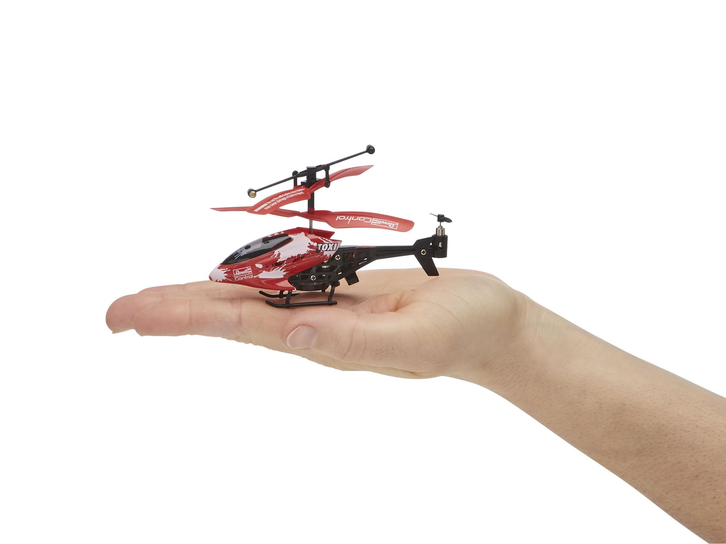Eine Hand hält einen kleinen, rot-schwarzen Spielzeug-Hubschrauber. Der Hubschrauber hat zwei Rotoren.