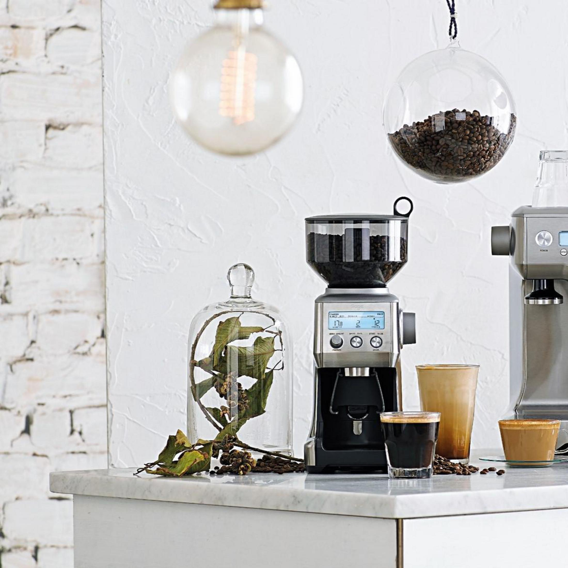 Kaffeestation-Setup mit einer Kaffeemühle, Espressomaschine, Glaskuppel und Kaffeebohnen.