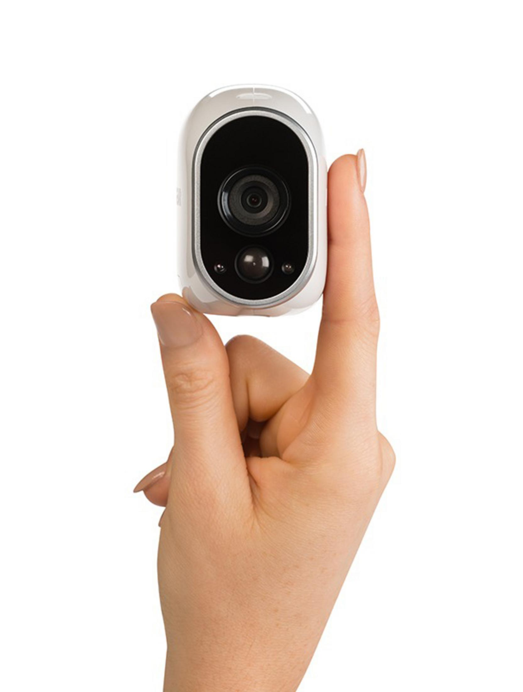 Una piccola telecamera di sicurezza bianca tenuta in mano su sfondo bianco.