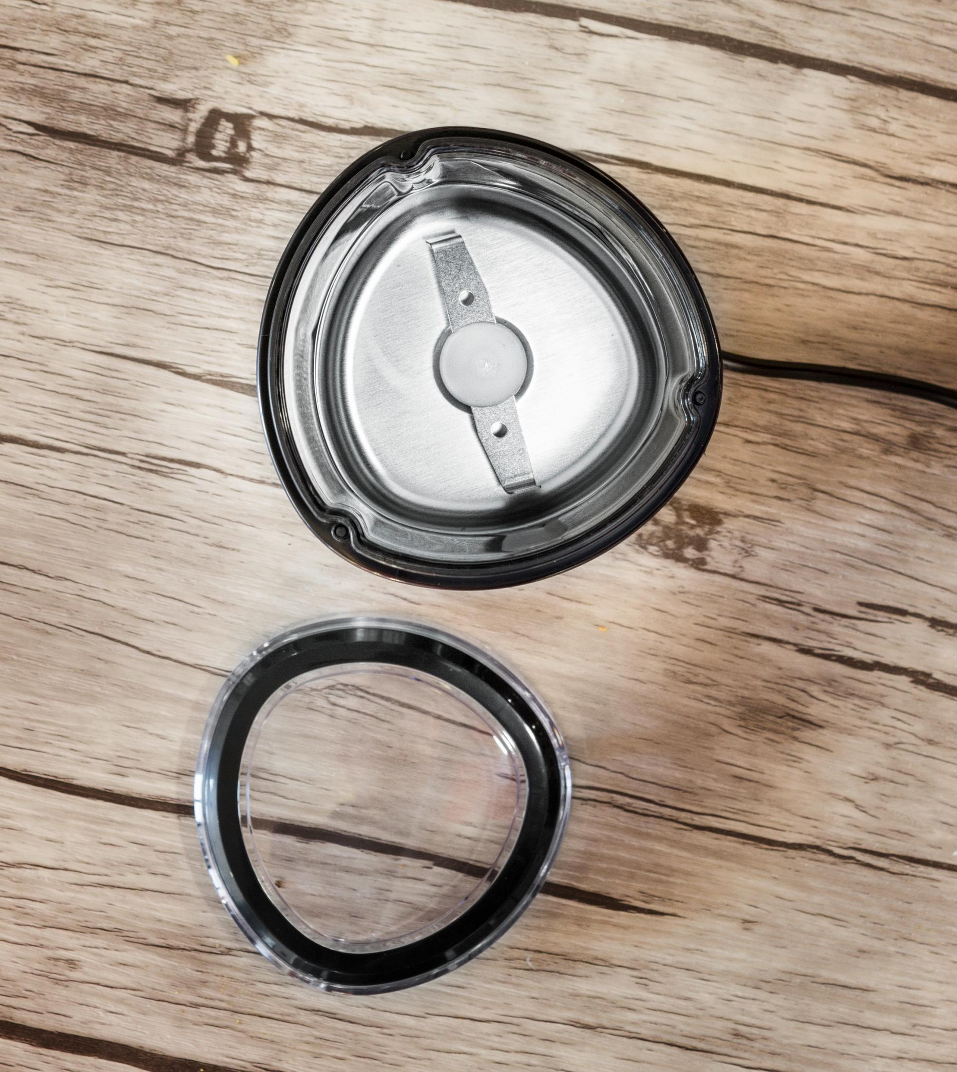 Widok z góry na młynek do kawy bez pokrywki i pokrywkę obok.