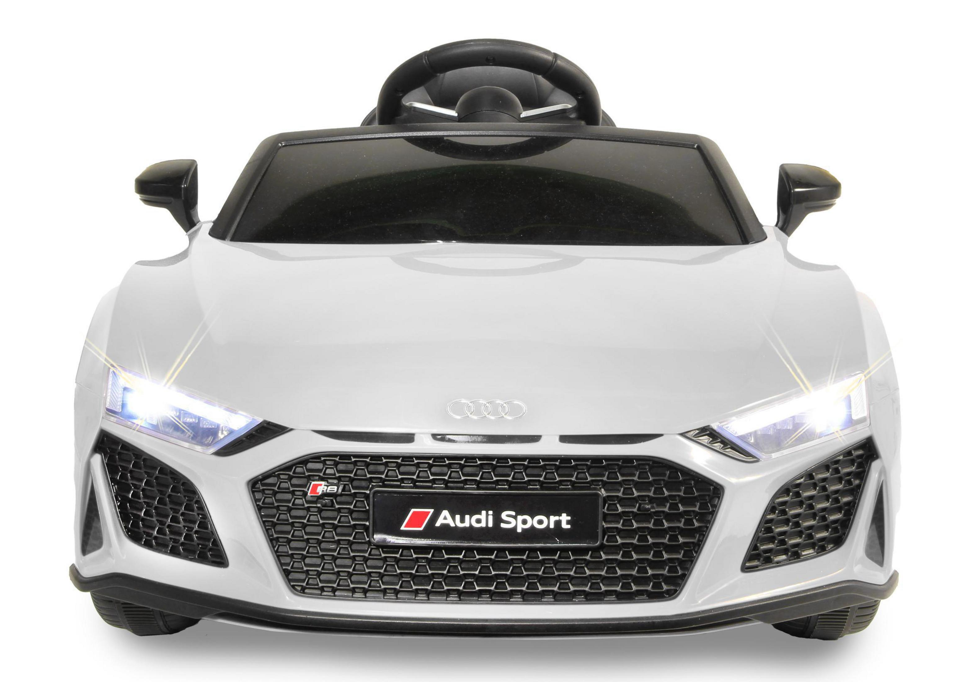 Weißes Spielzeugauto mit eingeschalteten Frontlichtern. 'Audi Sport'-Logo sichtbar.