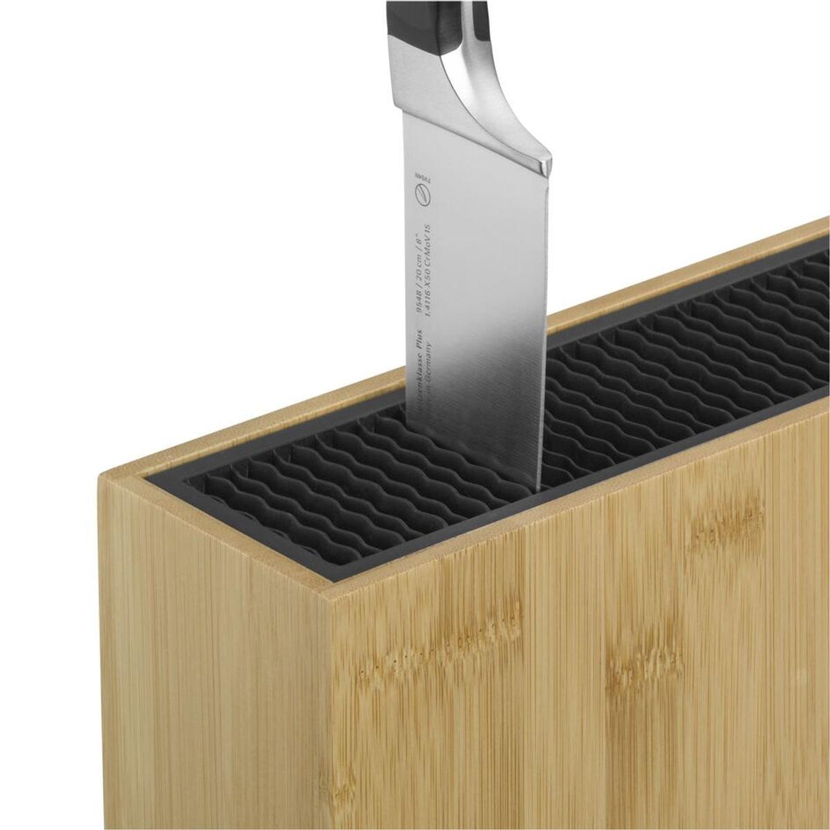 Un couteau est inséré dans un bloc de couteaux en bois. Le couteau a une lame argentée.
