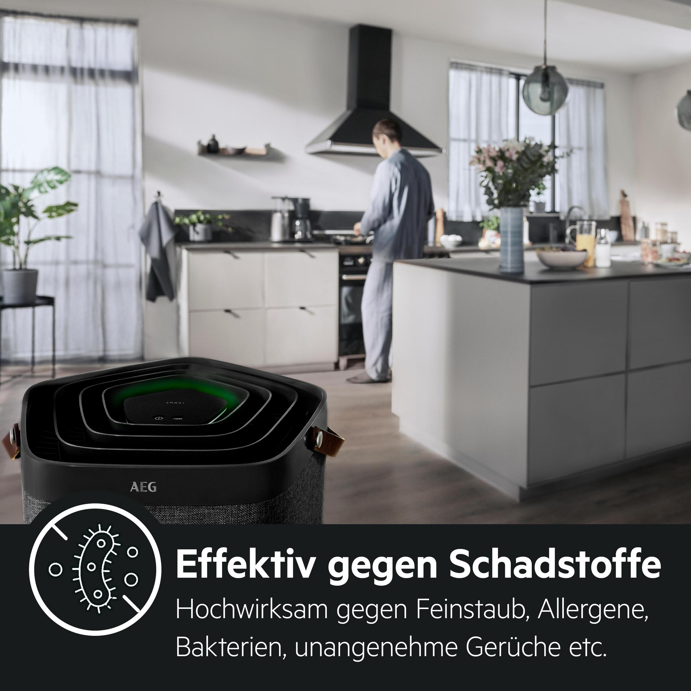 Luftreiniger in einer Küche. Eine Person ist im Hintergrund. Text: Wirksam gegen Schadstoffe.