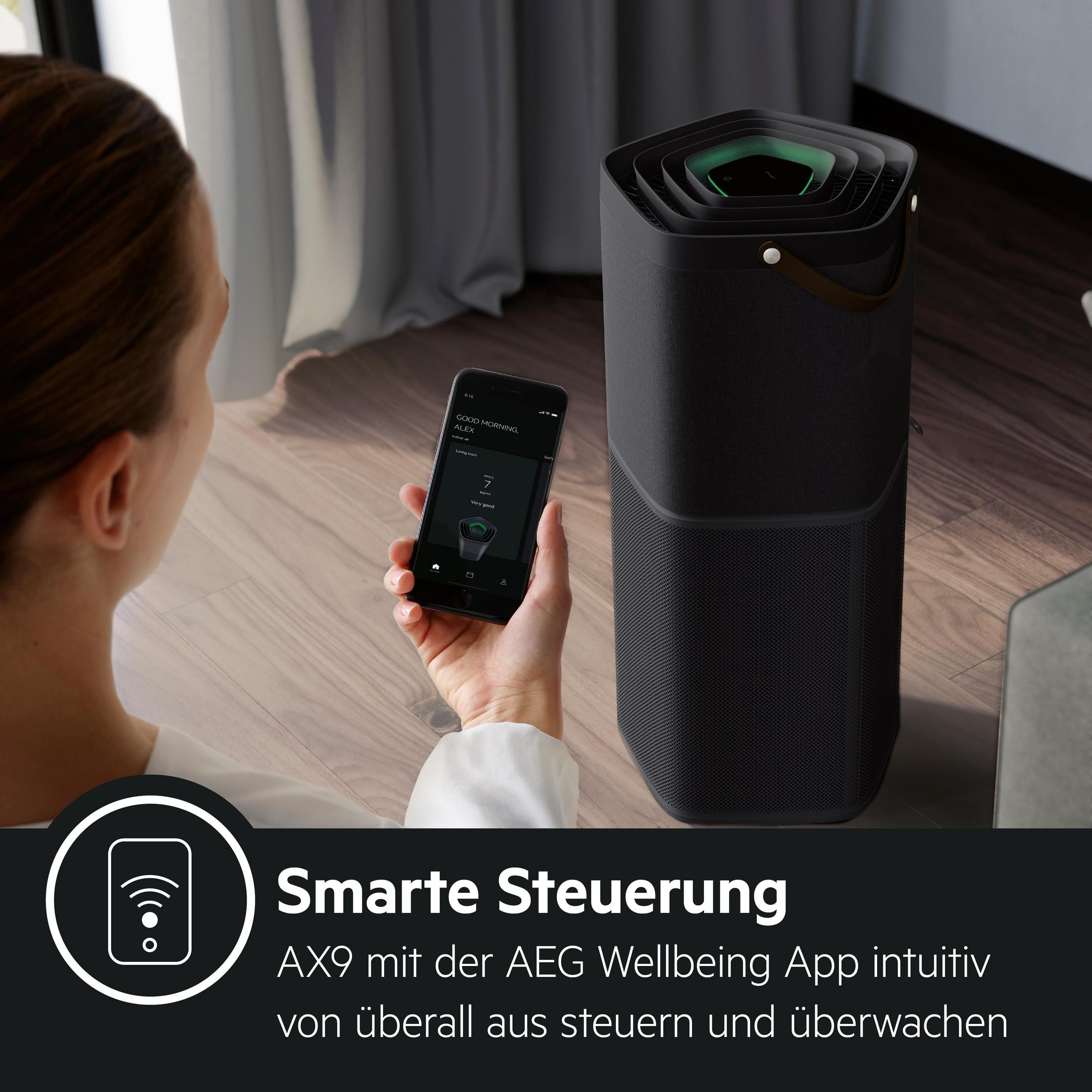 Frau hält Telefon, vor Luftreiniger. Text: Smarte Steuerung, AEG Wellbeing App.
