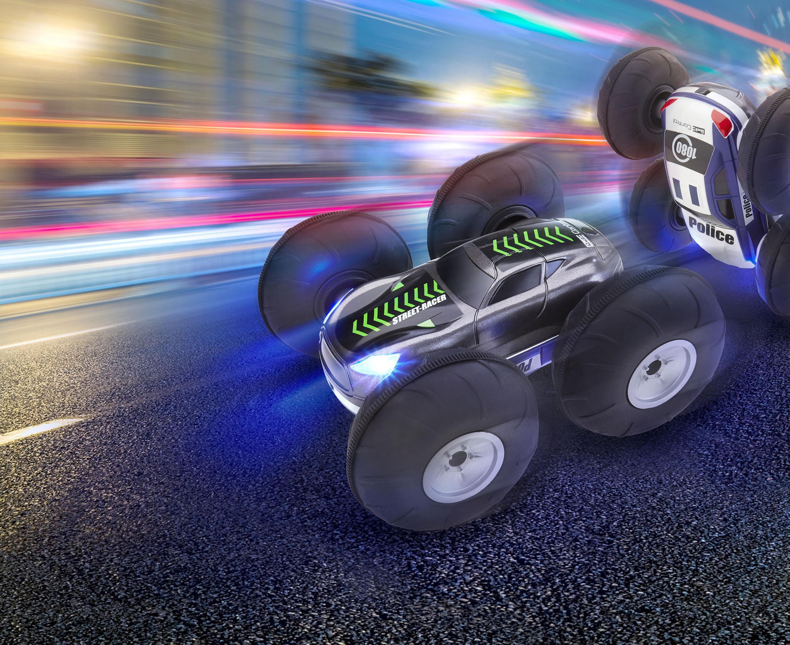 RC-Monstertrucks rasen auf einer dunklen Straße mit Bewegungsunschärfe.