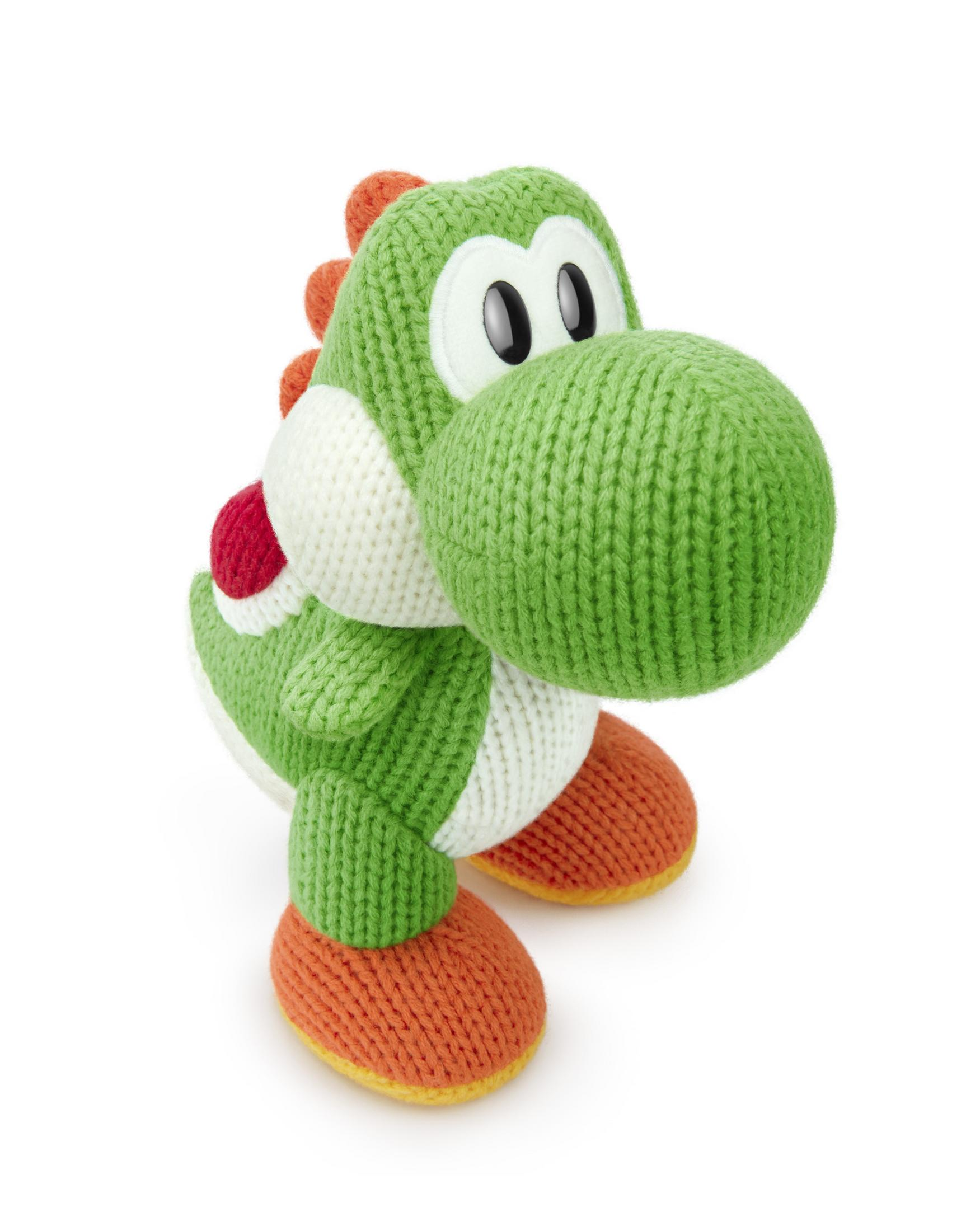 Gestricktes Yoshi-Spielzeug, grün mit weißem Bauch, rotem Panzer und orangen Schuhen. Es hat große Augen.