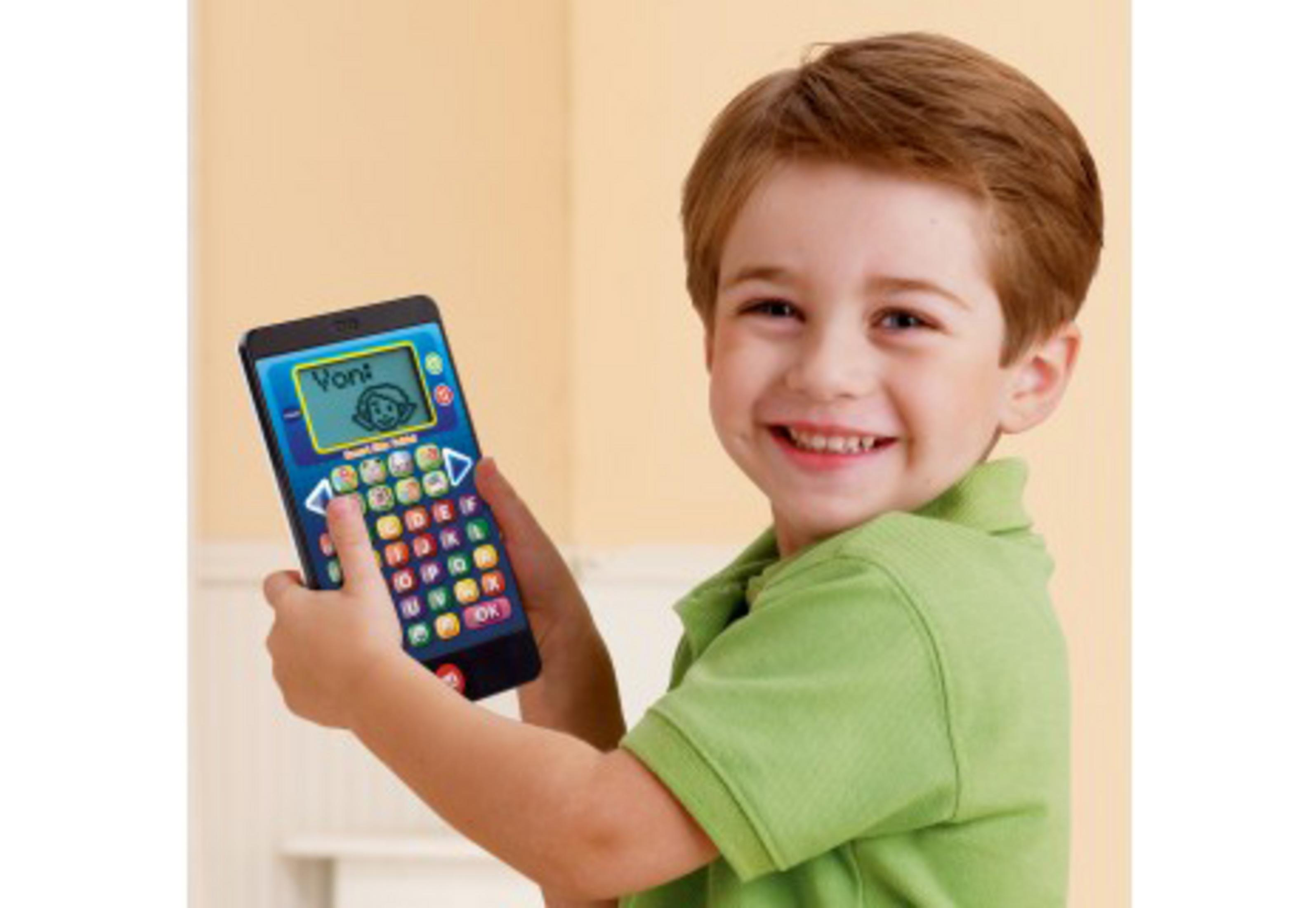 Ein junger Junge hält ein Spielzeugtelefon und lächelt. Das Telefon hat bunte Knöpfe und einen Bildschirm.