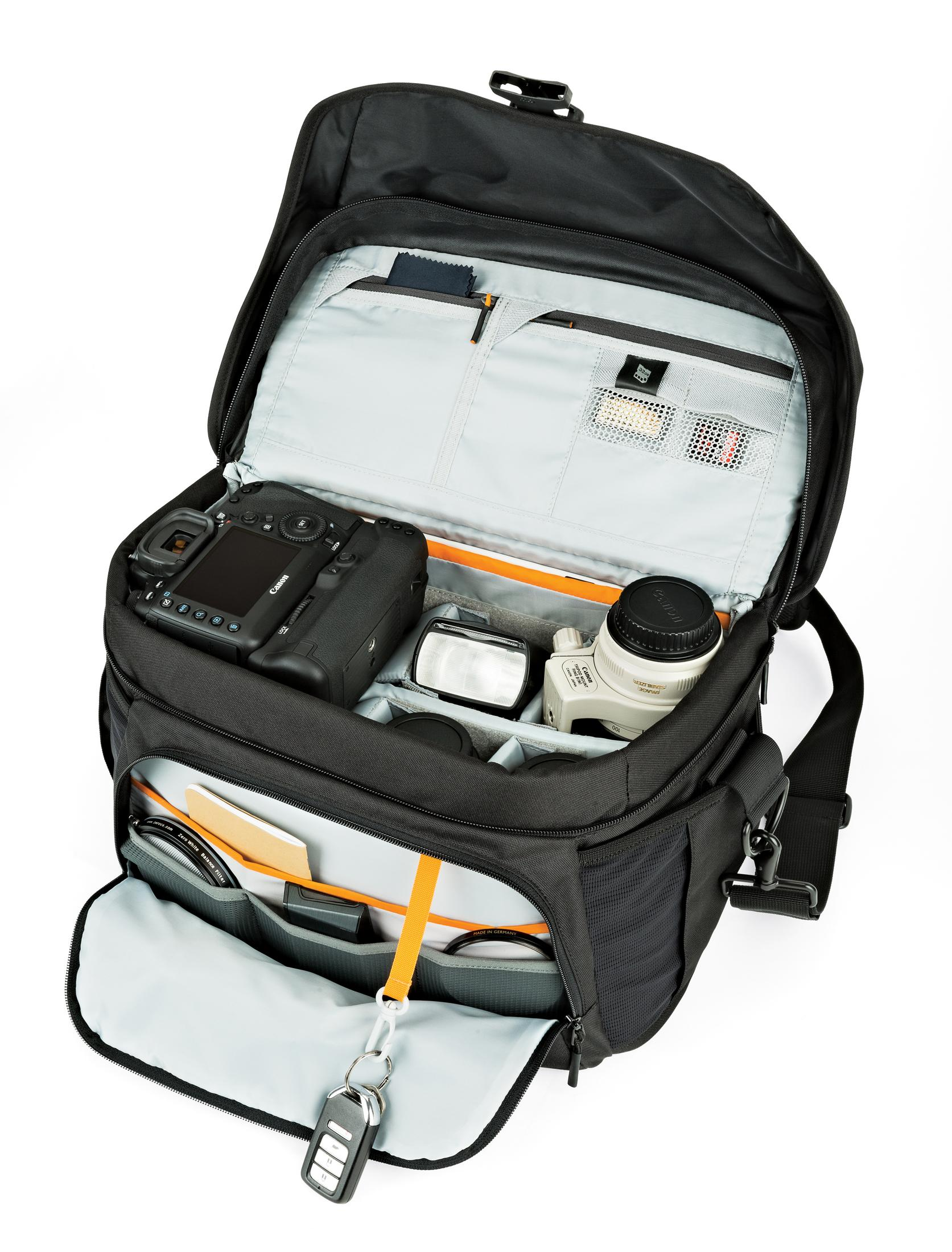 Black camera bag, open, with camera, lens, flash, accessories, and a white background.
