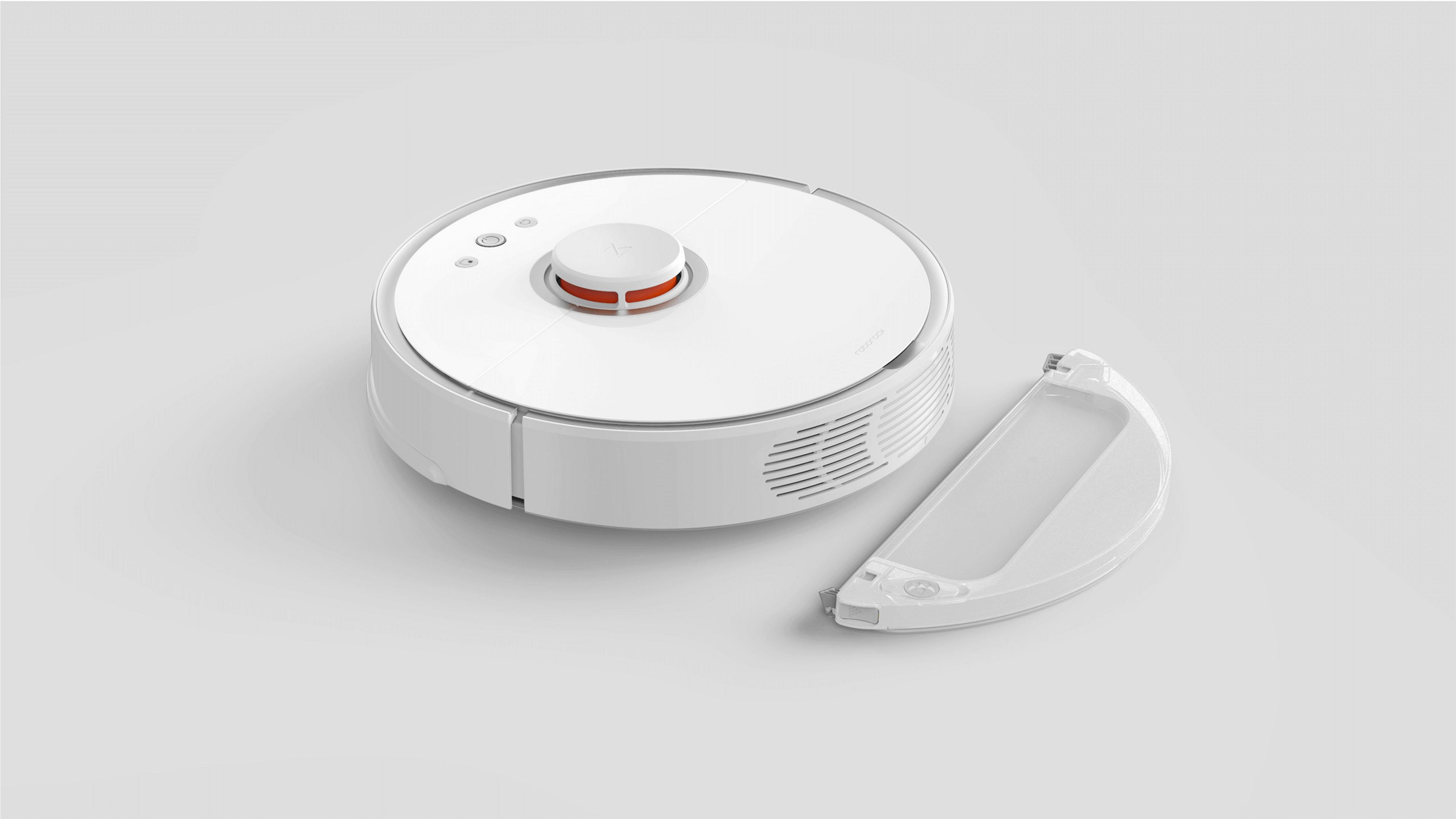 Ein weißer Roboter-Staubsauger mit separatem Staubbehälter auf hellgrauer Oberfläche.