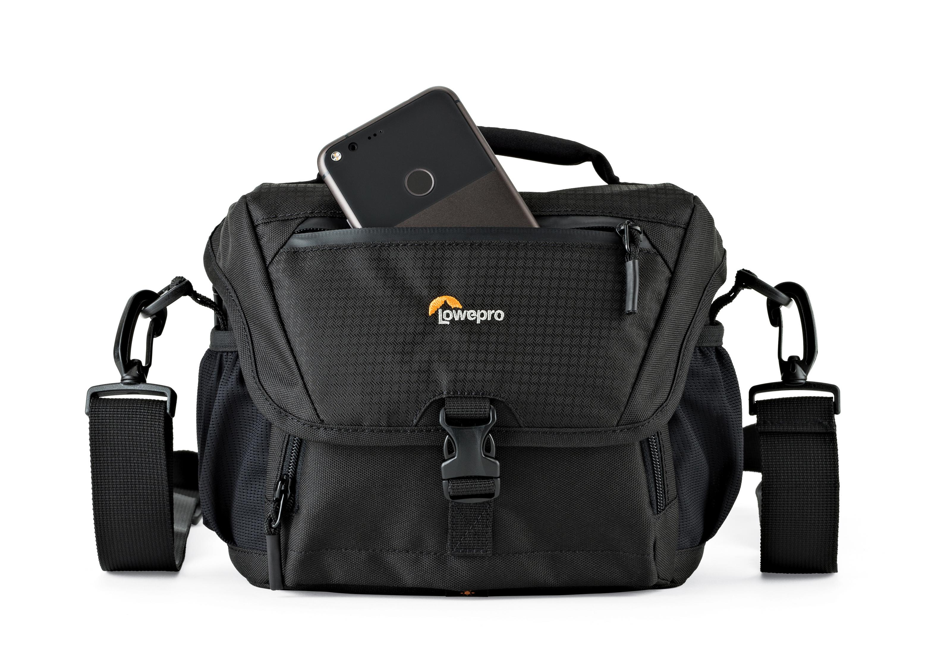 Schwarze Kameratasche mit einem Telefon in der Vordertasche. Weißer Hintergrund. Tasche hat einen Riemen.