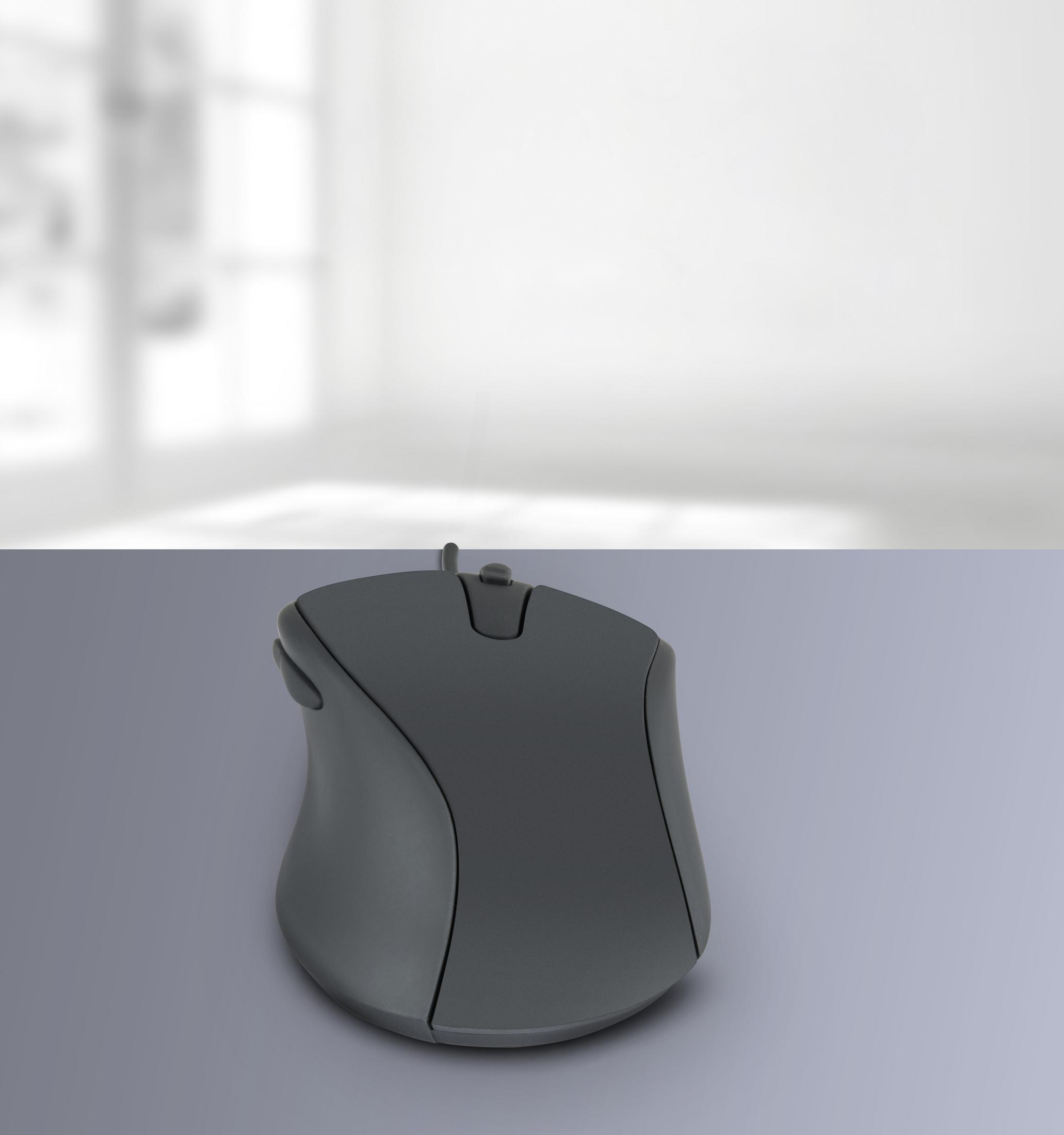 A dark gray computer mouse on a light gray surface. The background is blurred.