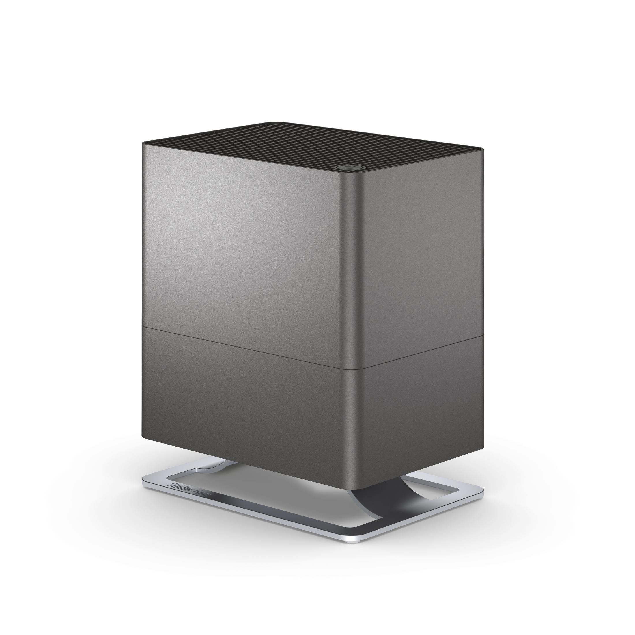 A dark gray air purifier is displayed on a white surface.