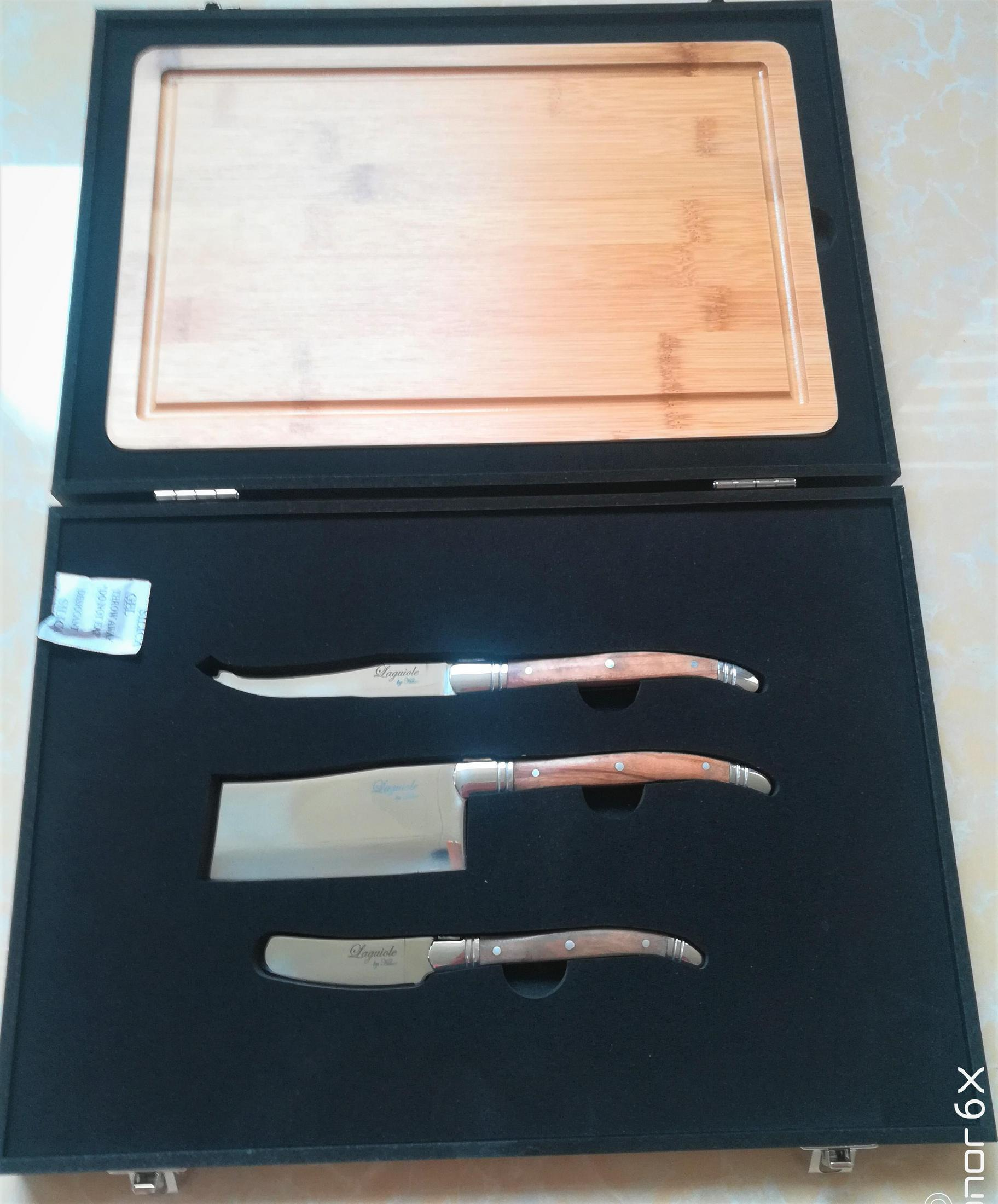 Ein Messerset und ein Schneidebrett in einer schwarzen Box. Die Messer haben Holzgriffe.