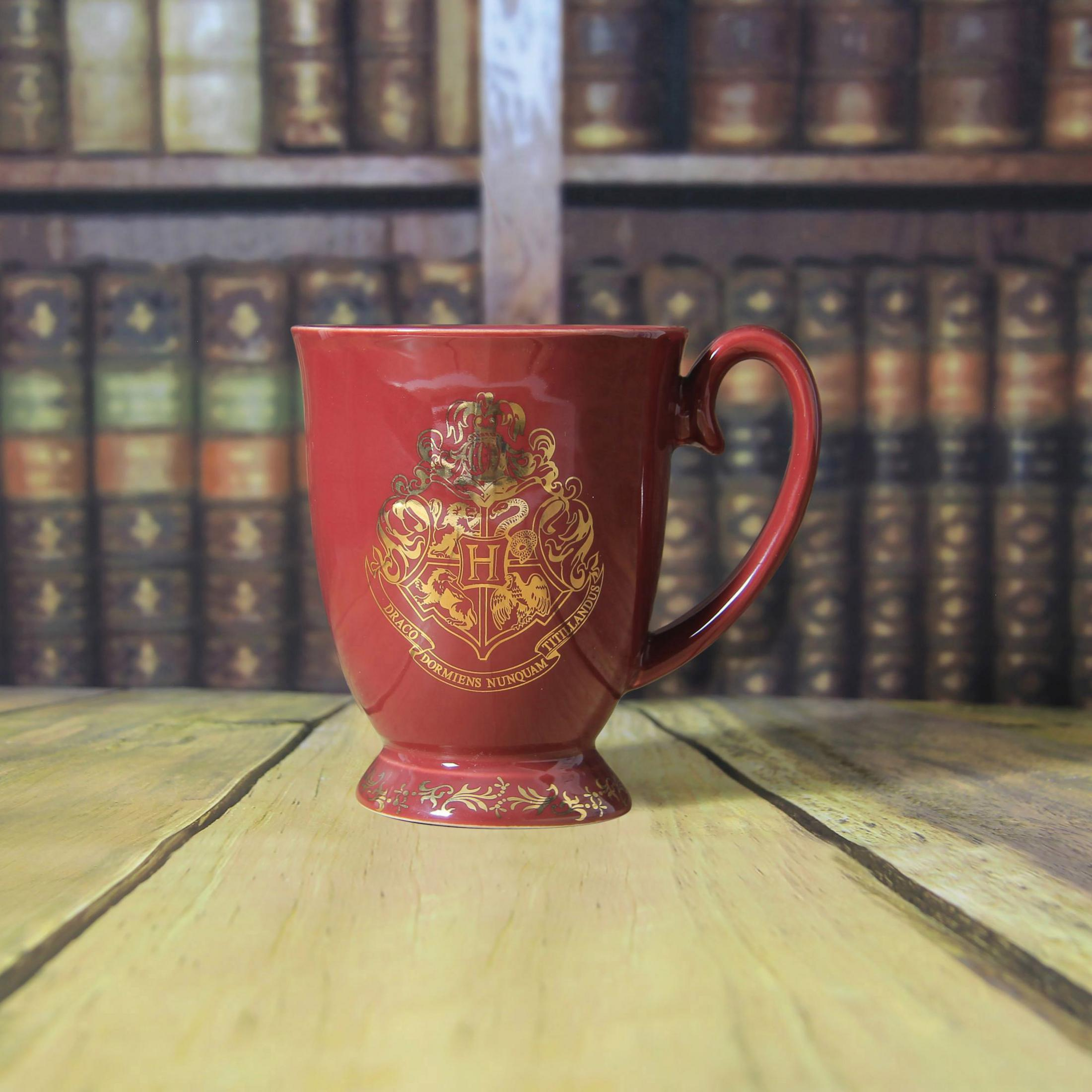 Roter Harry Potter-Becher mit dem Gryffindor-Wappen auf einem Holztisch.