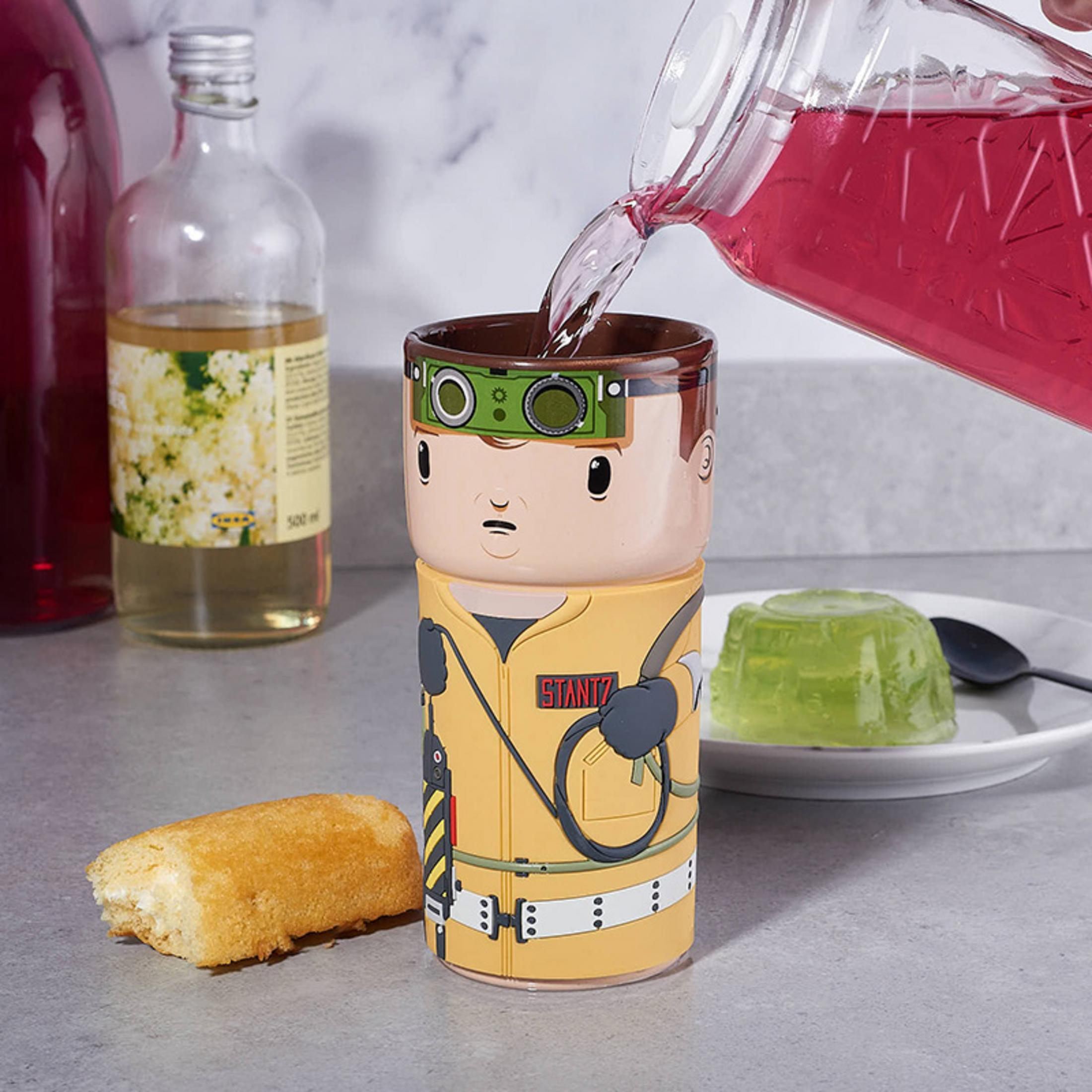 Ein Ghostbusters-Becher, in den Flüssigkeit gegossen wird, mit einem Twinkie und Gelee.
