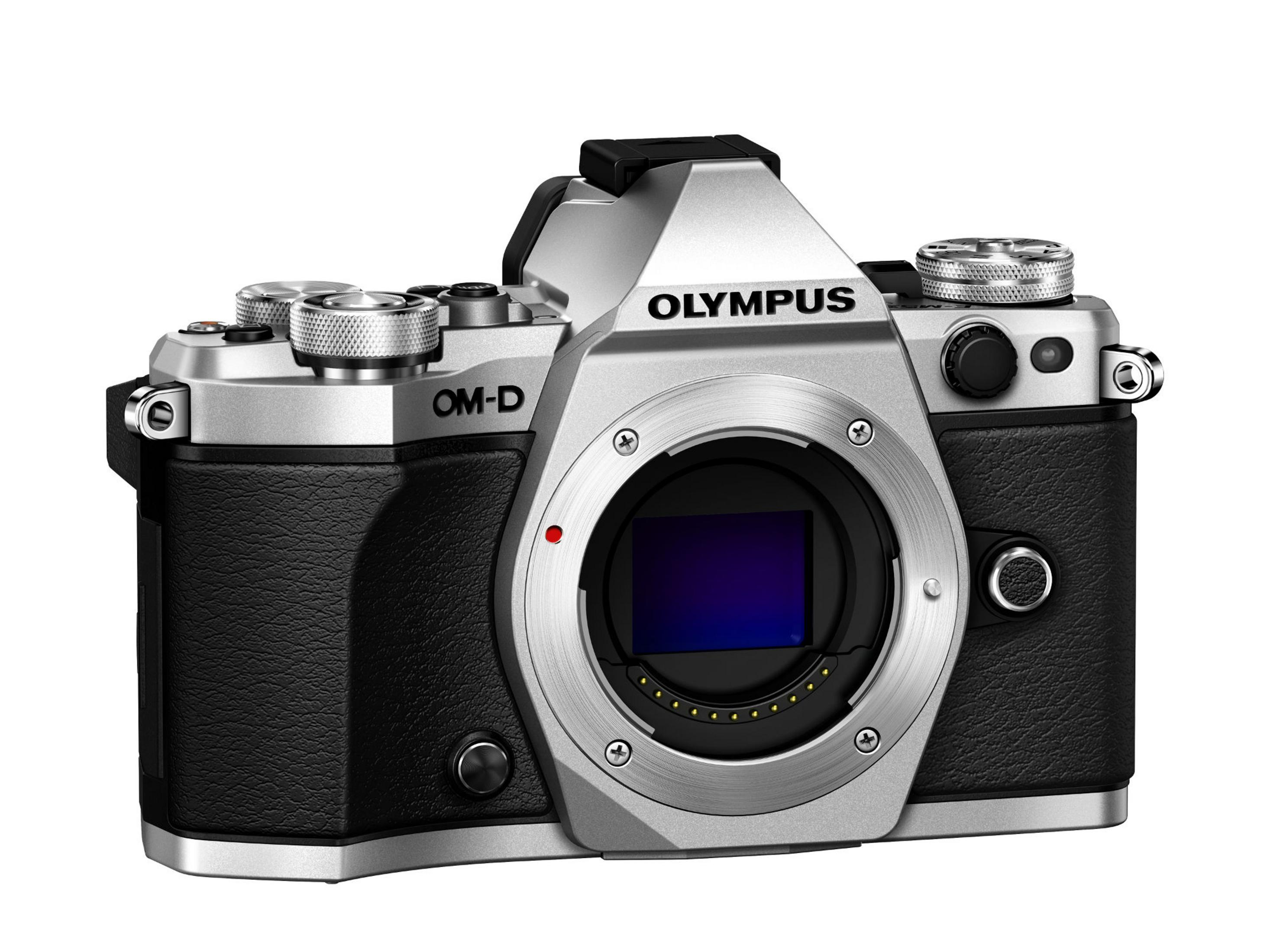 Silberne und schwarze Olympus OM-D Kamera mit Objektiv, auf weißer Oberfläche.