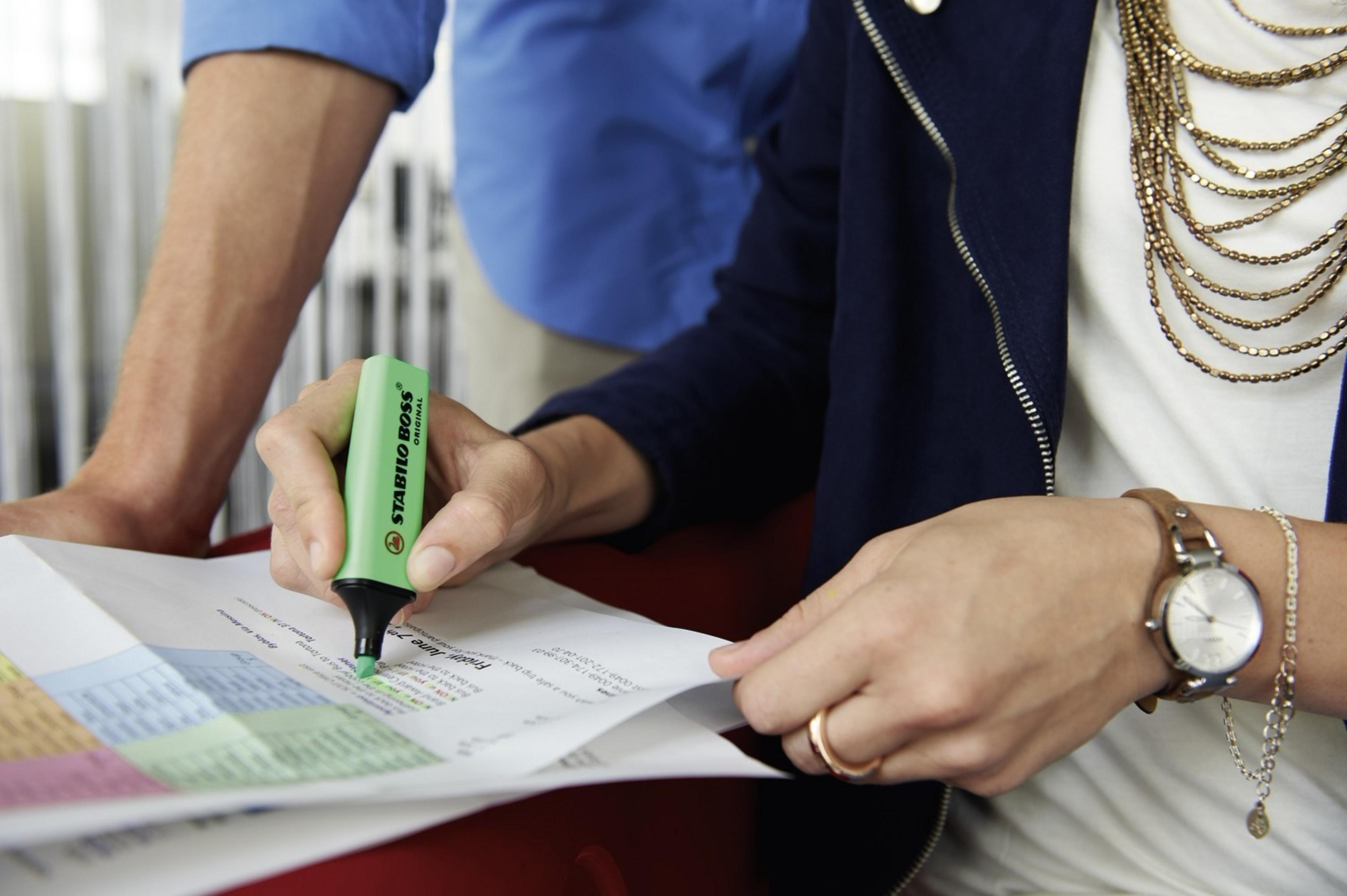 Persona che evidenzia il testo con un evidenziatore verde.