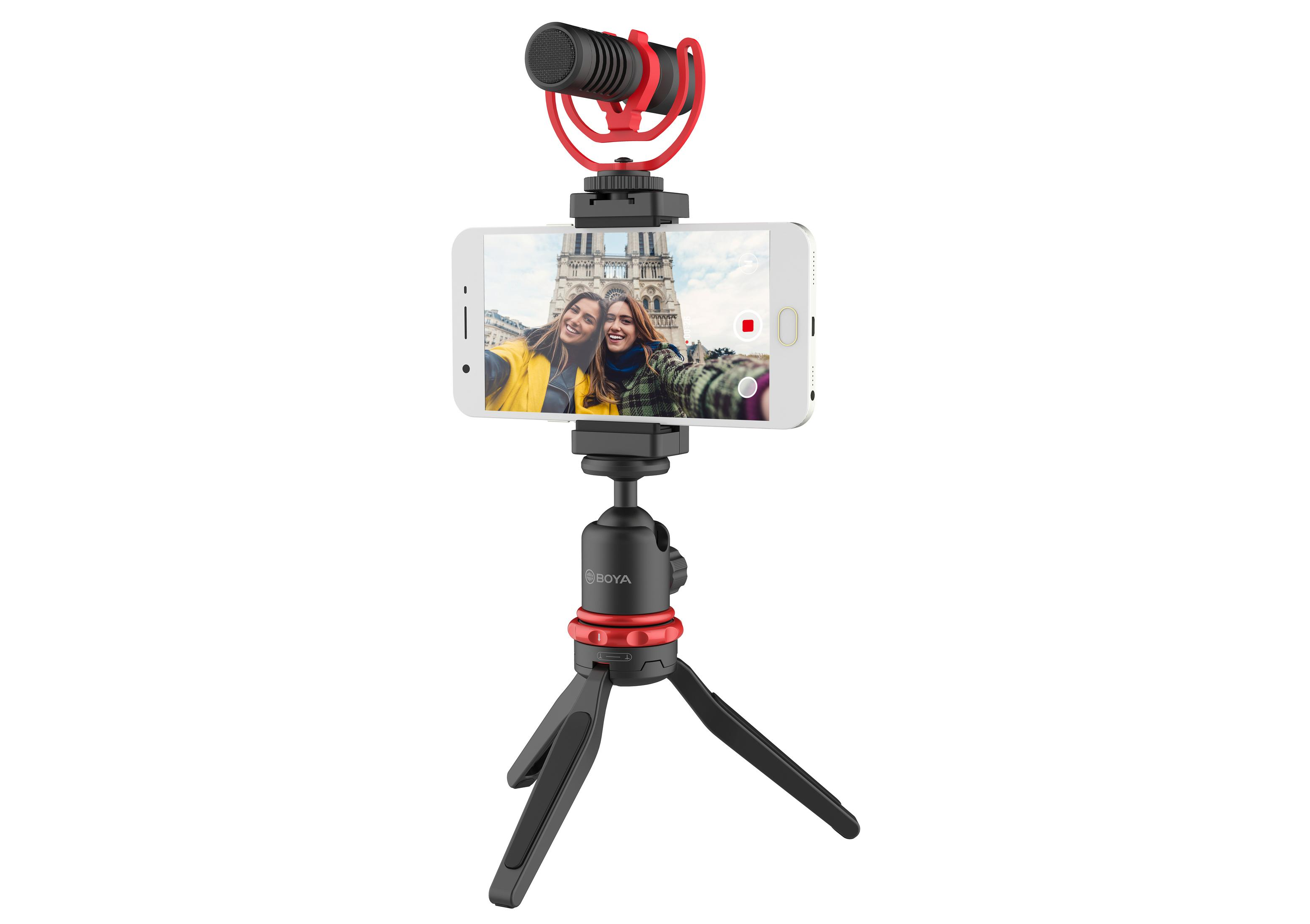 Smartphone en trípode con micrófono. Dos mujeres se hacen un selfie.