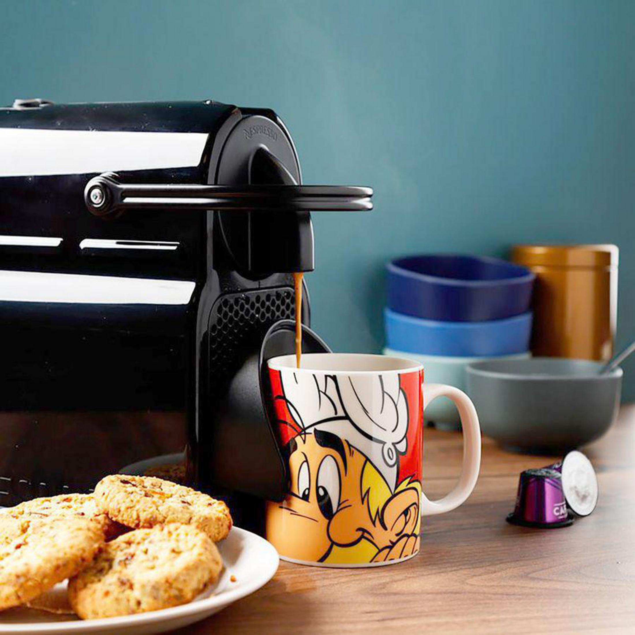 Kaffeemaschine gießt Kaffee in eine Tasse mit einer Comicfigur. Kekse und Schalen stehen auf dem Tisch.