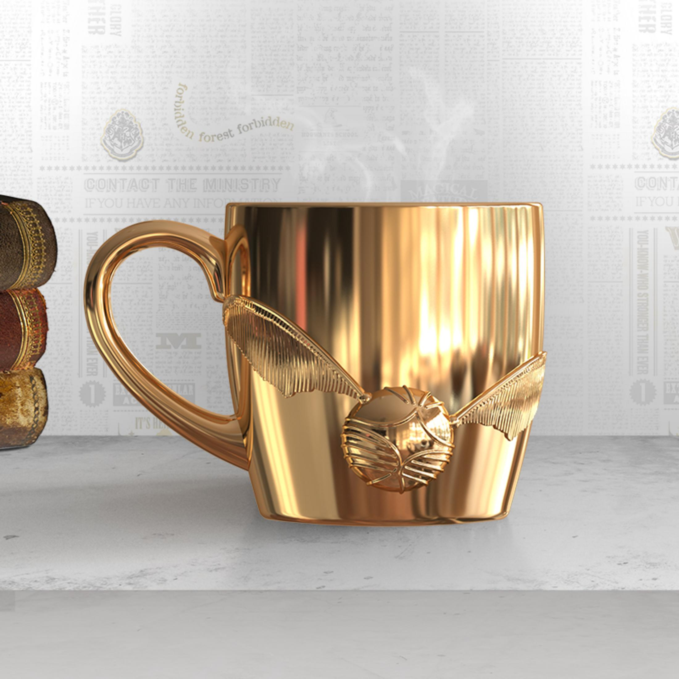 Goldene Tasse mit Flügeln und Ball, Dampf steigt auf, auf einer Oberfläche mit Zeitungen im Hintergrund.