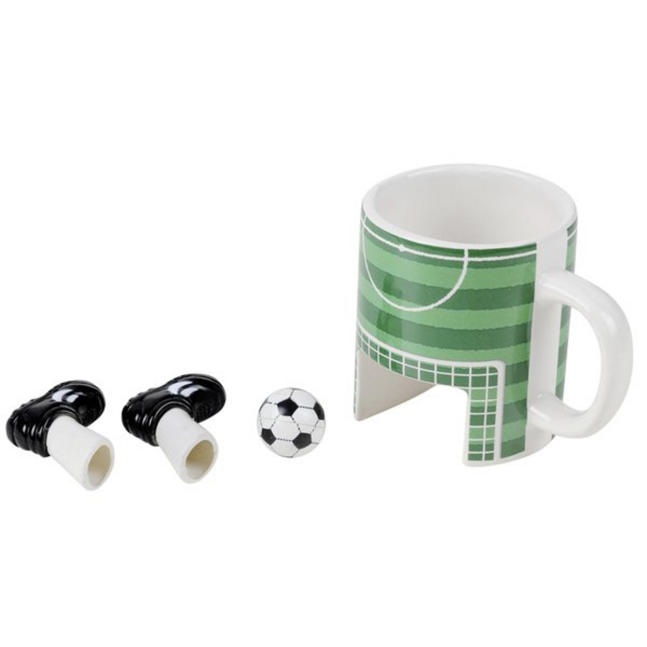 Eine Tasse mit Fußballfeld-Design, einem Fußball und Fußballschuhen.