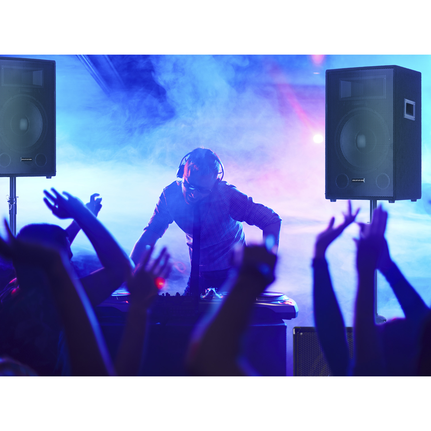DJ in einem Club mit Lautsprechern, Leuten und blau-roter Beleuchtung.