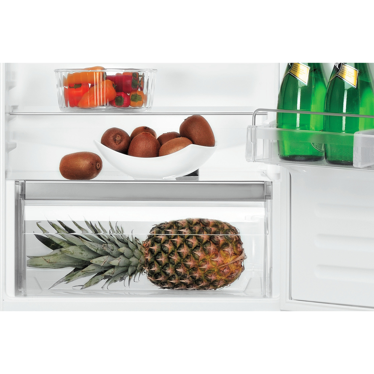 Nahaufnahme des Kühlschrankinneren. Ananas in der Schublade, Kiwis in der Schüssel und Paprika im Behälter.
