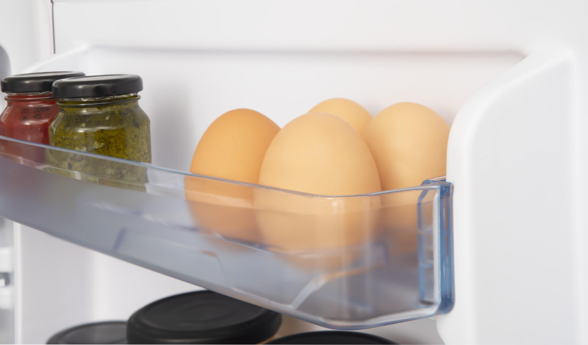 Offener Kühlschrank. Gläser und Eier in einer Schublade.