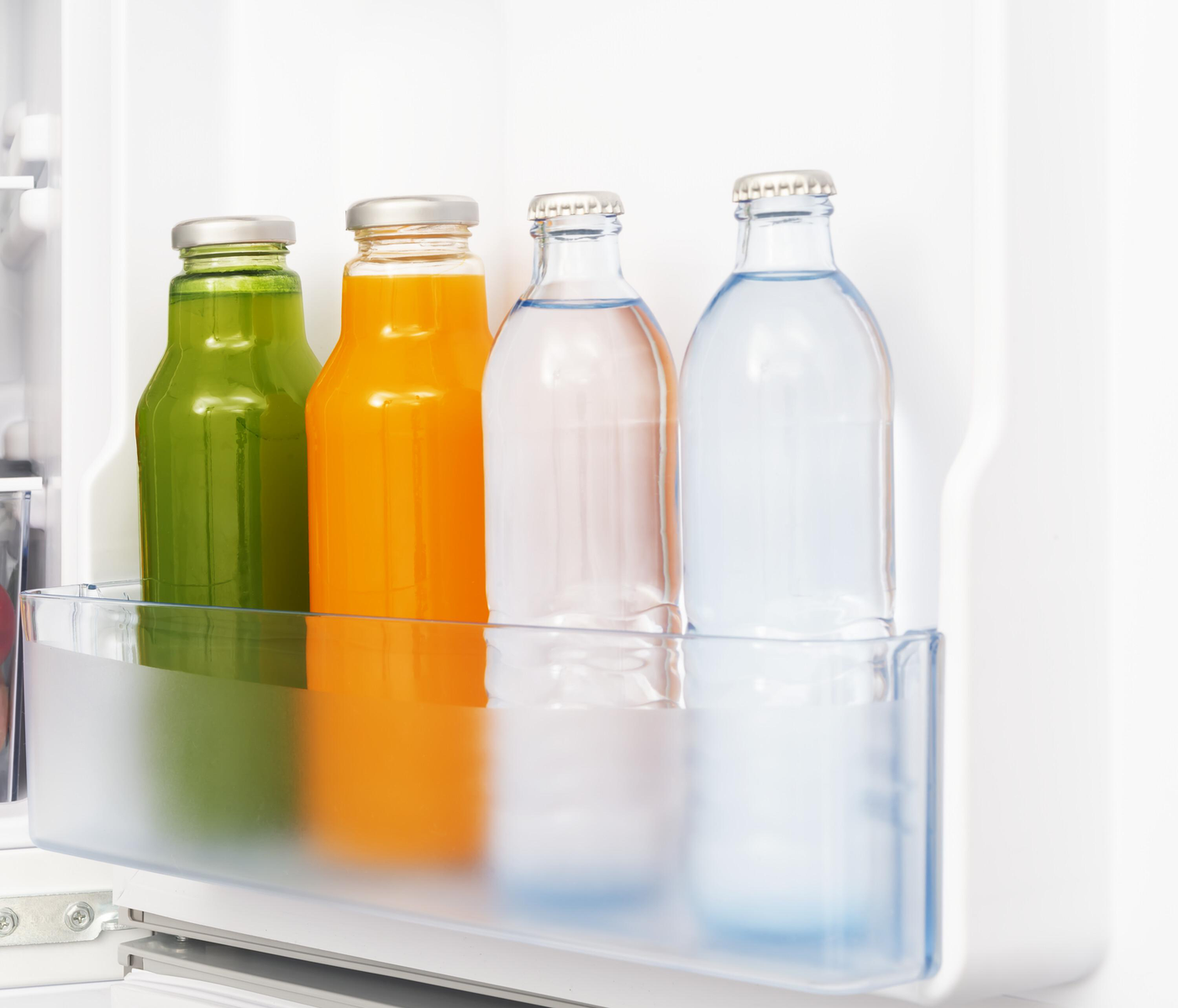 Im Kühlschrank: grüne und orangefarbene Saftflaschen, Wasserflaschen.