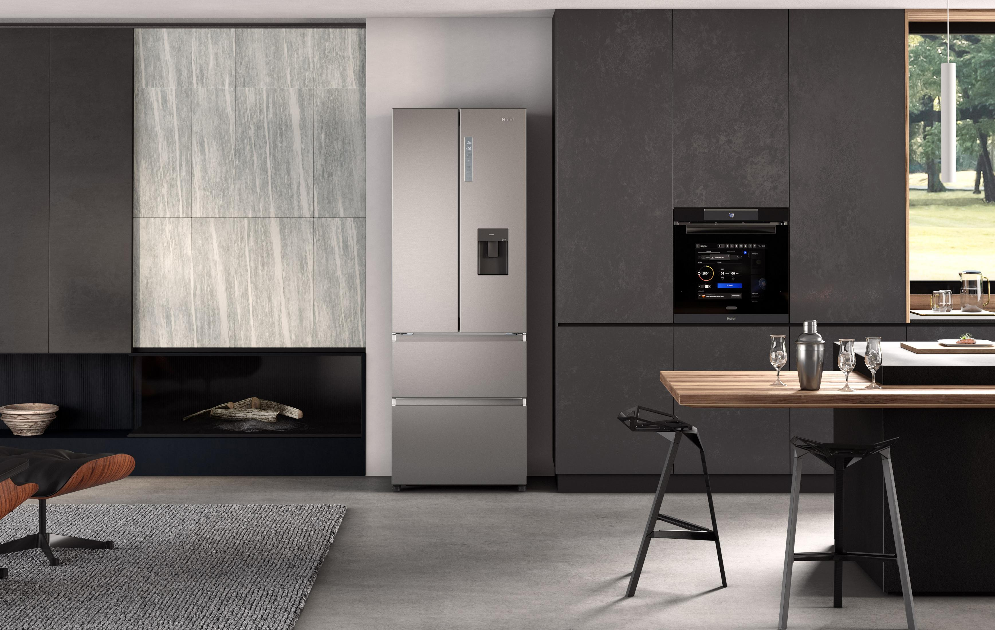 Cocina moderna con refrigerador de acero inoxidable, armarios negros y horno. Mesa de madera y dos sillas.