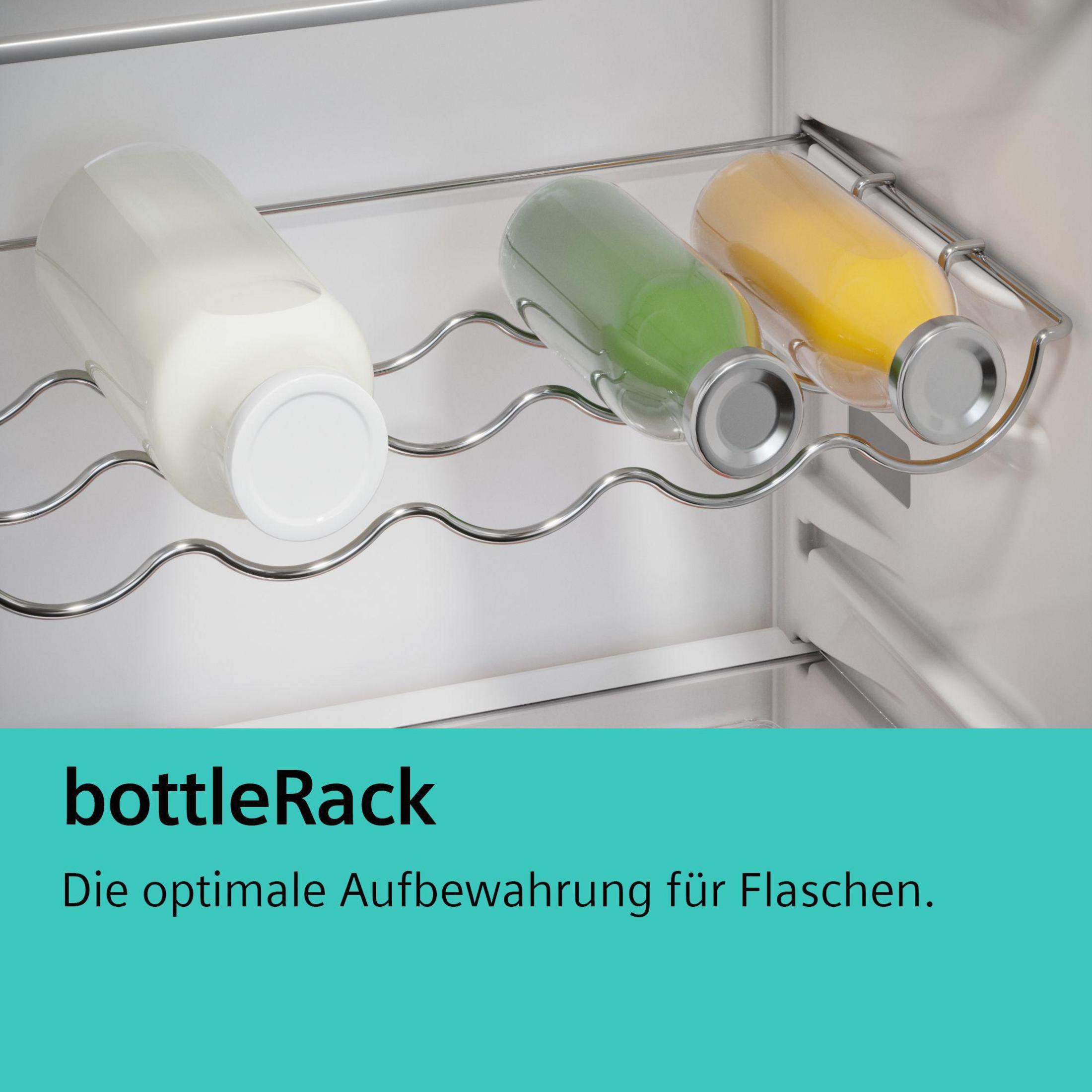 Trzy szklane butelki w różnych kolorach w metalowym stojaku w lodówce.