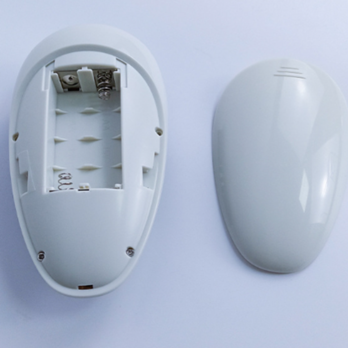 Ein offenes, weißes, ovales Gerät mit sichtbarem Batteriefach und Deckel.