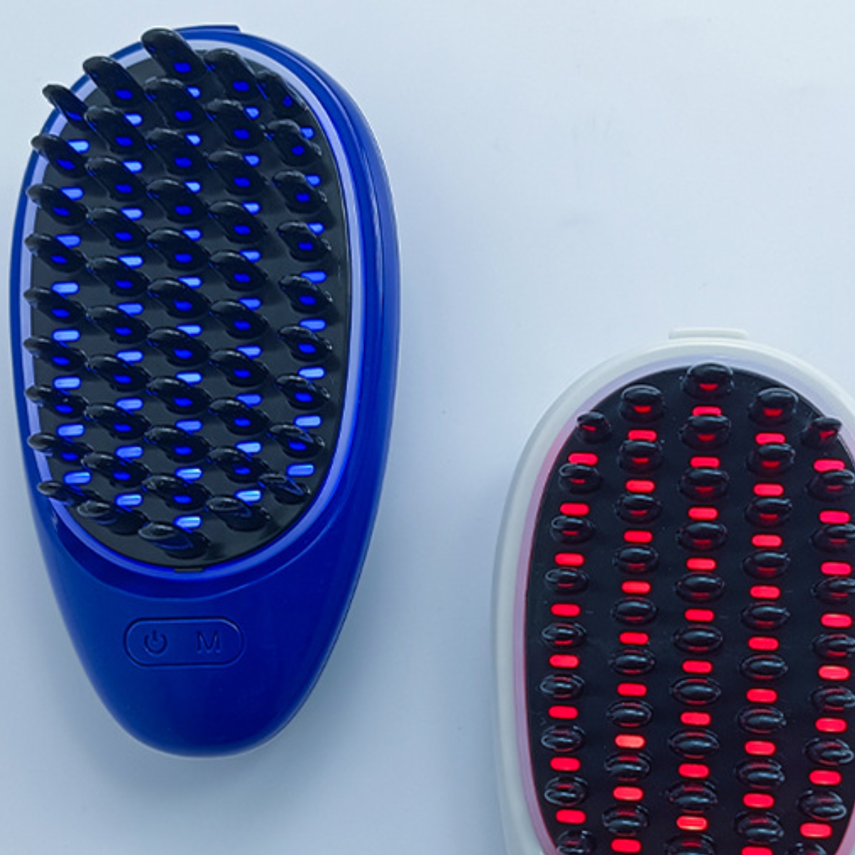 Zwei Haarbürsten, eine blaue mit blauen Lichtern, eine weiße mit roten Lichtern.