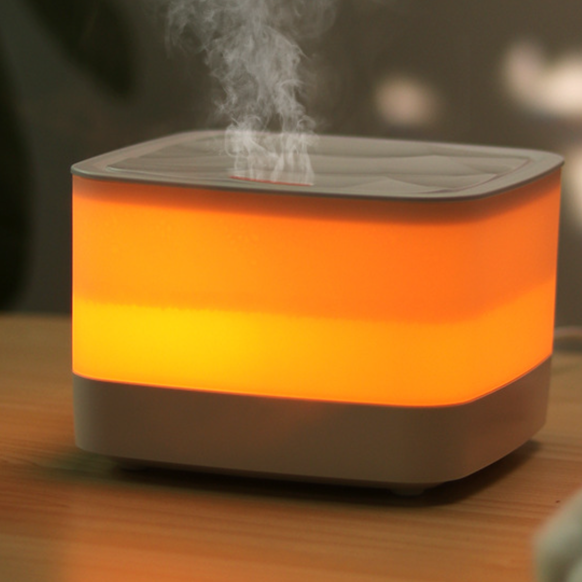Quadratischer, beleuchteter Luftbefeuchter mit orangefarbenem Glühen, Dampf erzeugend.